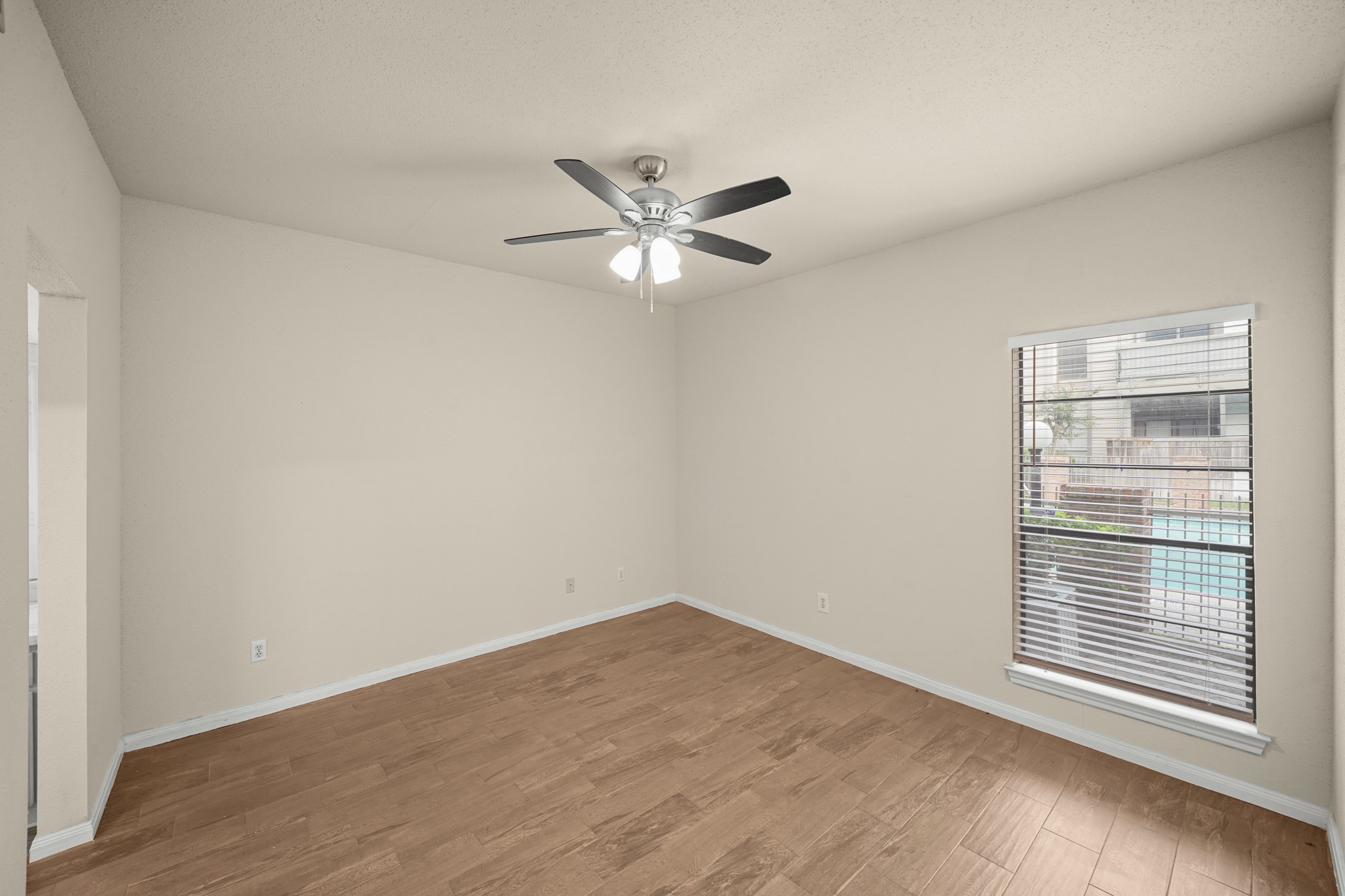 A bright bedroom featuring wood like flooring and a modern ceiling fan for comfort.