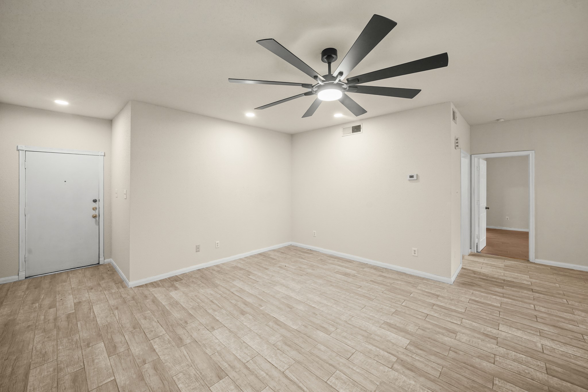 Spacious, modern living area features recessed lighting, a large ceiling fan, and an open doorway leading to the bedroom.