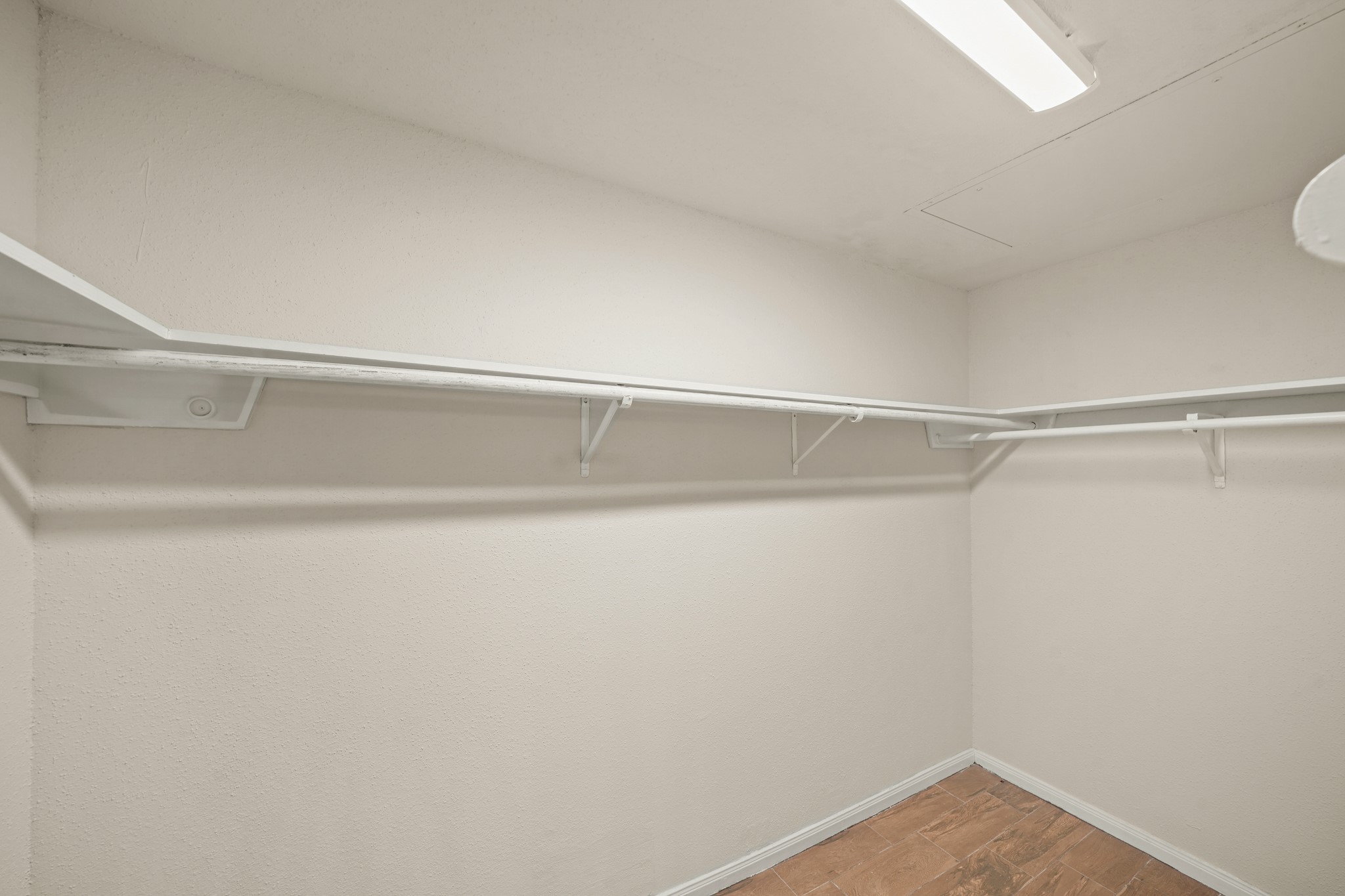 Spacious walk-in closet with white shelves and ample hanging space.