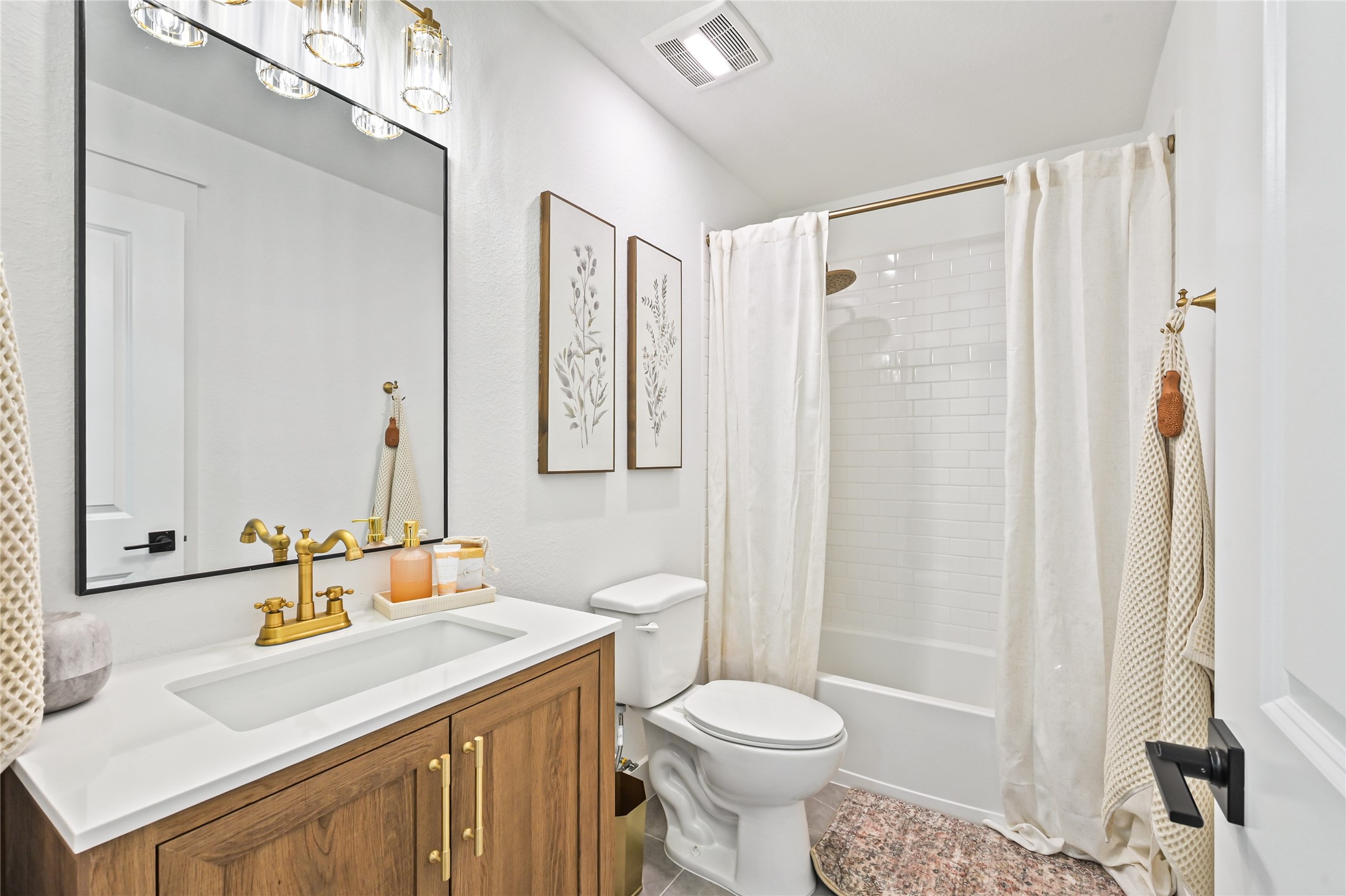 gorgeous natural wood vanity with a sleek white countertop, an undermount sink, and elegant brushed-gold fixtures and cabinet hardware.