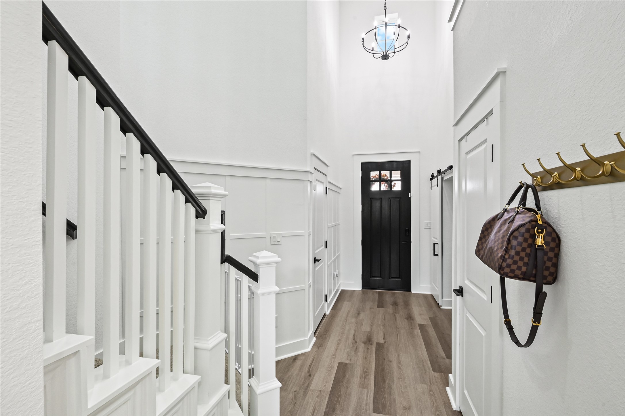 Bright foyer features soaring ceilings, crisp white walls, decorative wainscoting