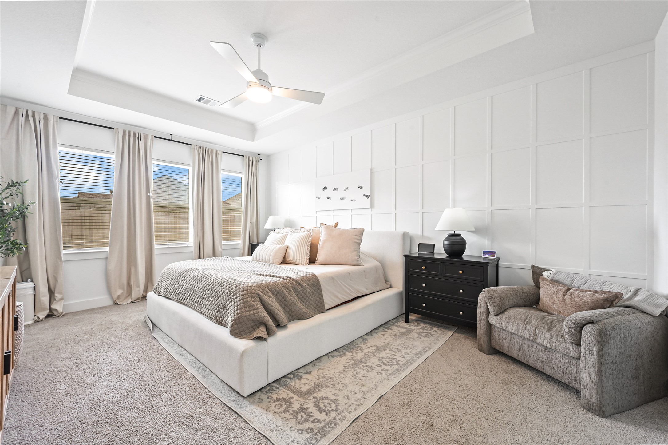 stunning primary bedroom suite, A beautiful tray ceiling with crown molding adds, floor-to-ceiling board-and-batten accent wall, Large windows