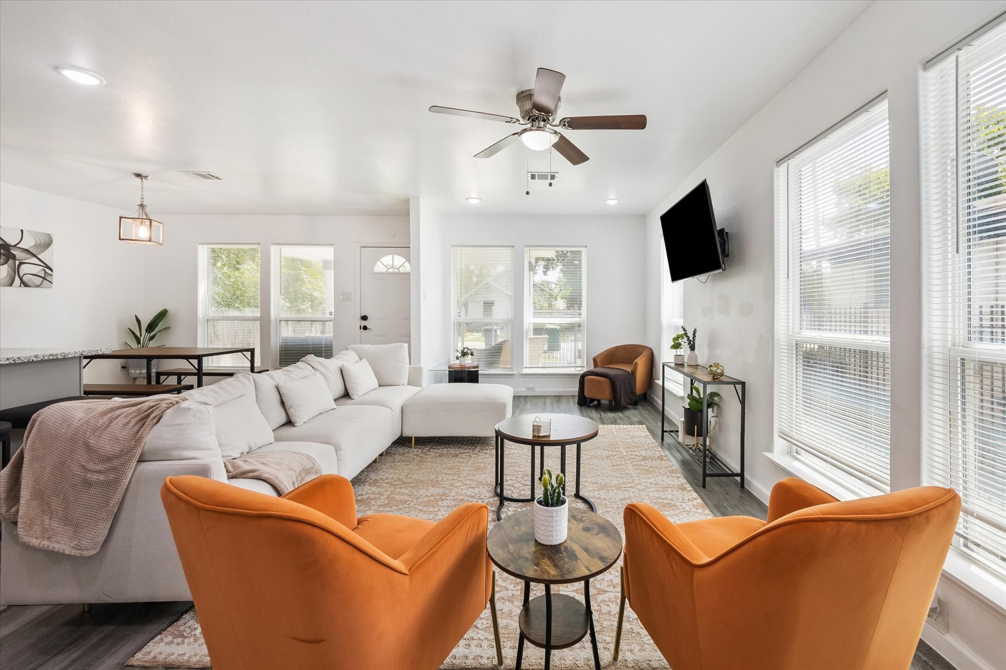 The living area is surrounded by oversized windows that fill the space with natural light. Neutral finishes and an open layout create a versatile setting for both everyday comfort and entertaining.