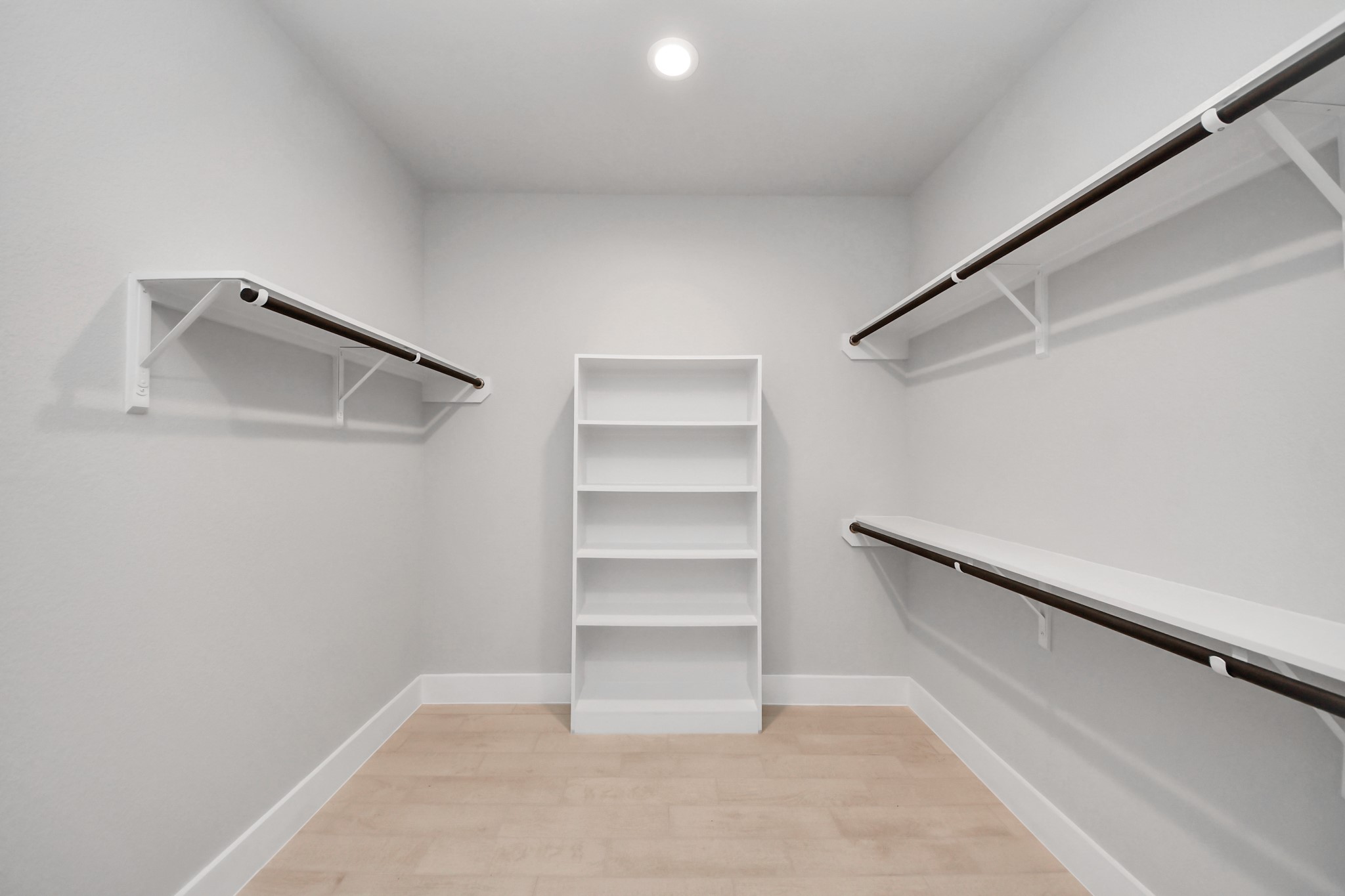 Walk-in closet that epitomizes luxury and practicality. This generously sized space features built-in shelving, offering abundant room for impeccable organization. High ceilings and recessed lighting create a bright and welcoming ambiance. Sample photo of completed home with similar floor plan. Actual colors and selections may vary.