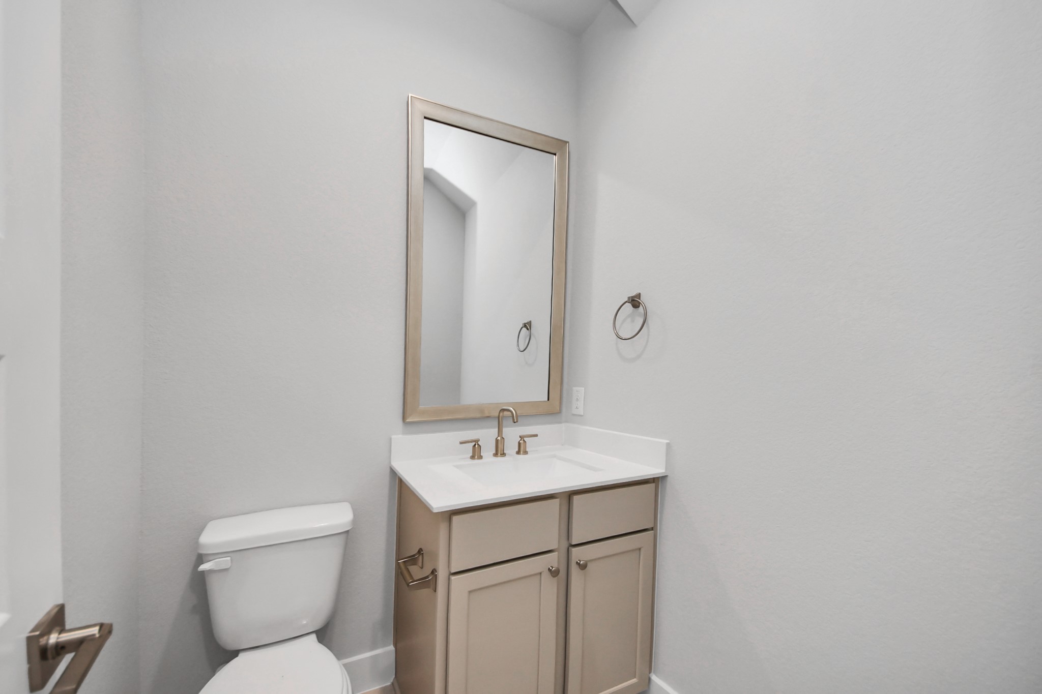 Sophisticated half bathroom adorned with contemporary finishes. The elegant 5-panel door welcomes you to a space where style meets functionality. Notice the sleek hardware accents that add a touch of modern charm. The vanity boasts light-colored countertops, beautifully complemented by a tasteful vanity light, creating a well-lit and inviting atmosphere. Sample photo of completed home with similar floor plan. Actual colors and selections may vary.