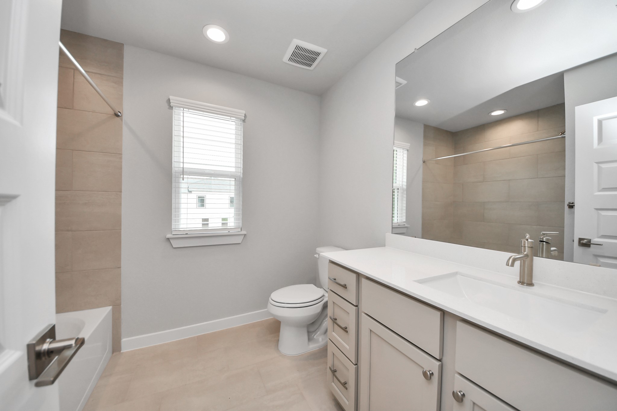 Secondary bath features tile flooring, walk-in shower with tile surround, light stained wood cabinets, beautiful light countertop. Sample photo of completed home with similar floor plan. Actual colors and selections may vary.