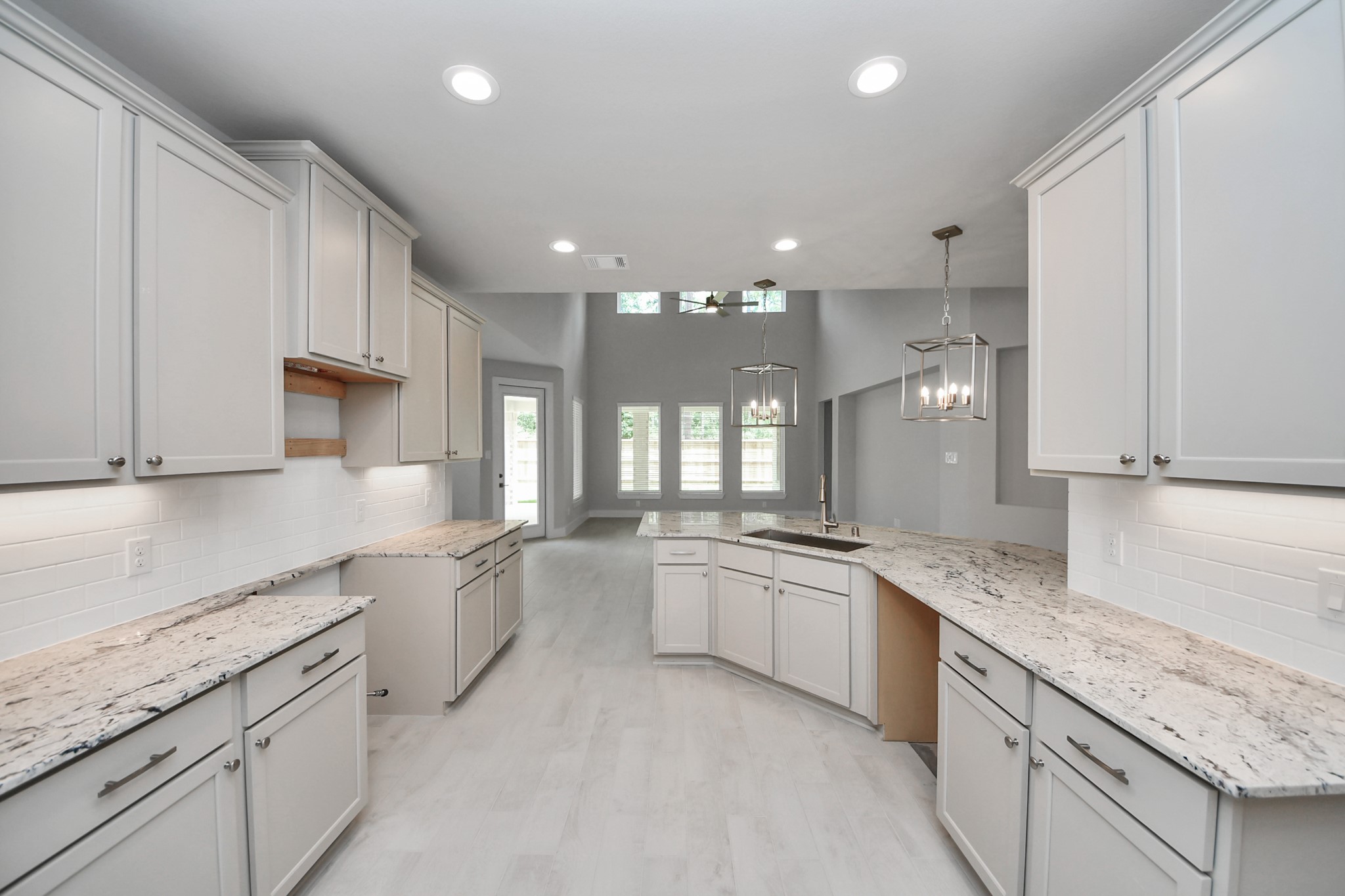 This kitchen is by far any chefs dream! This spacious kitchen features high ceilings, light stained wood cabinets, granite countertop, SS appliances, modern tile backsplash, recessed lighting, extended counter space, and a walk-in pantry all overlooking your huge family room. Sample photo of completed home with similar floor plan. Actual colors and selections may vary.