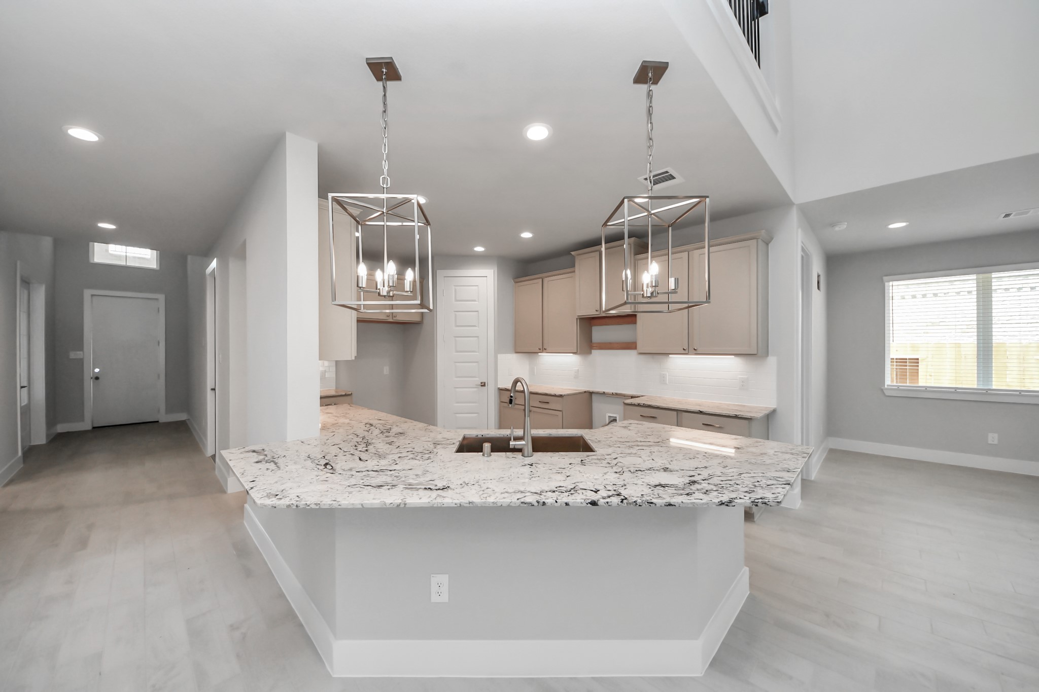 This kitchen is truly a chef's dream! This haven Boasts high ceilings, recessed & pendant lighting, stained wood cabinets, granite countertops, stainless steel appliances, a modern tile backsplash.  All of this overlooks your expansive family room, creating a perfect space for culinary delights and family gatherings. Sample photo of completed home with similar floor plan. Actual colors and selections may vary.