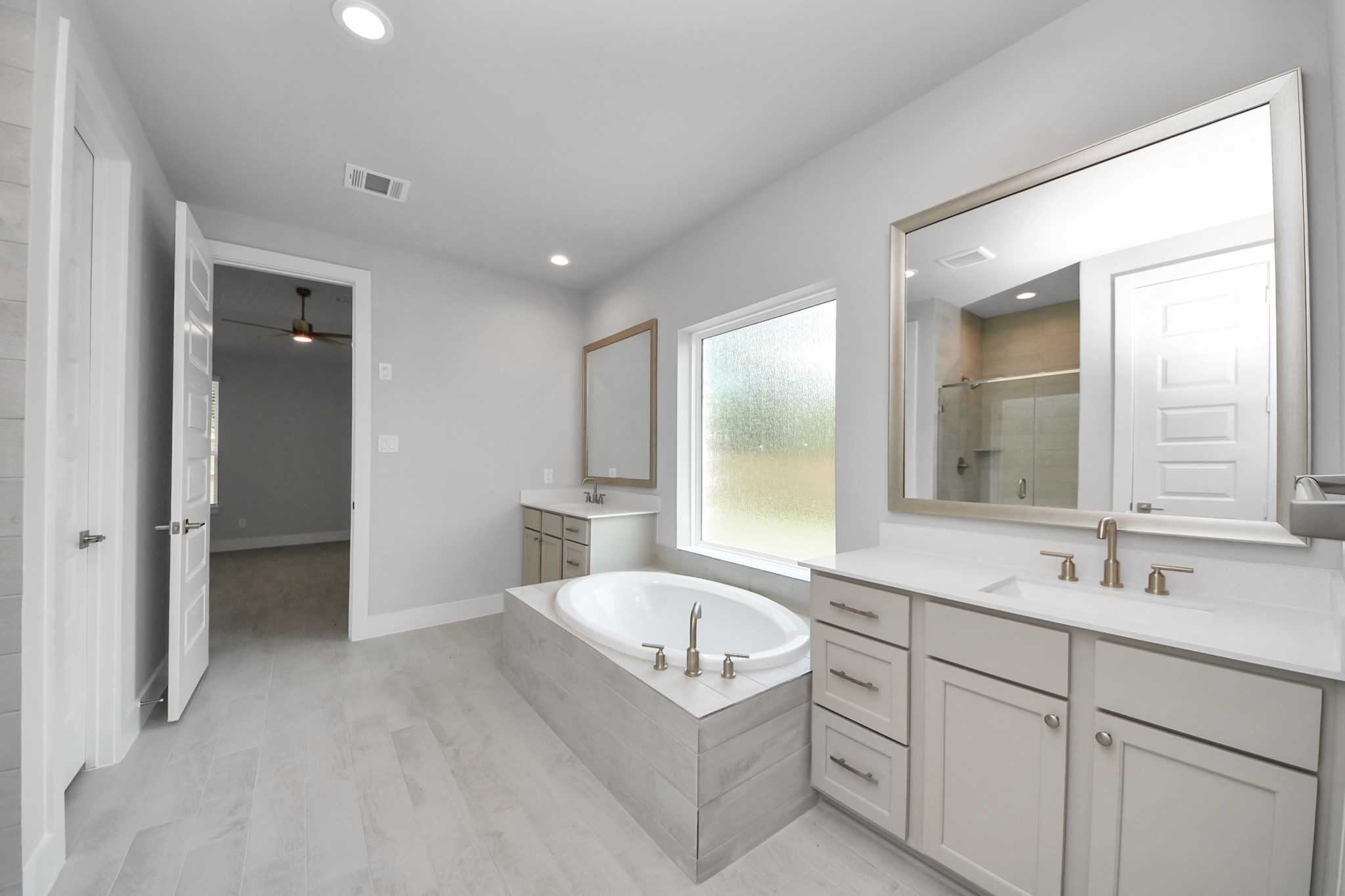 Elevate your daily routine at the elegant vanity, now equipped with double sinks, light countertops, modern hardware, and beautiful recessed lights. Sample photo of completed home with similar floor plan. Actual colors and selections may vary.