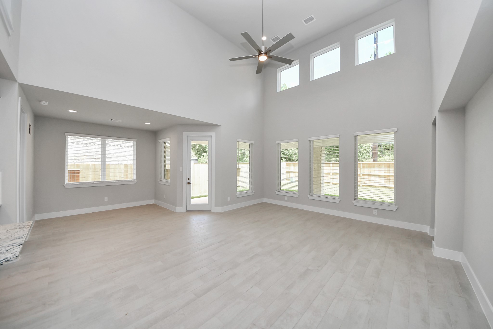 Relax and unwind in this inviting family room, illuminated by abundant natural light streaming in through tall windows, complemented by high ceilings and stunning flooring. Stay comfortable year-round with the gentle breeze from the ceiling fan, creating the perfect atmosphere for family gatherings. Sample photo of completed home with similar floor plan. Actual colors and selections may vary.