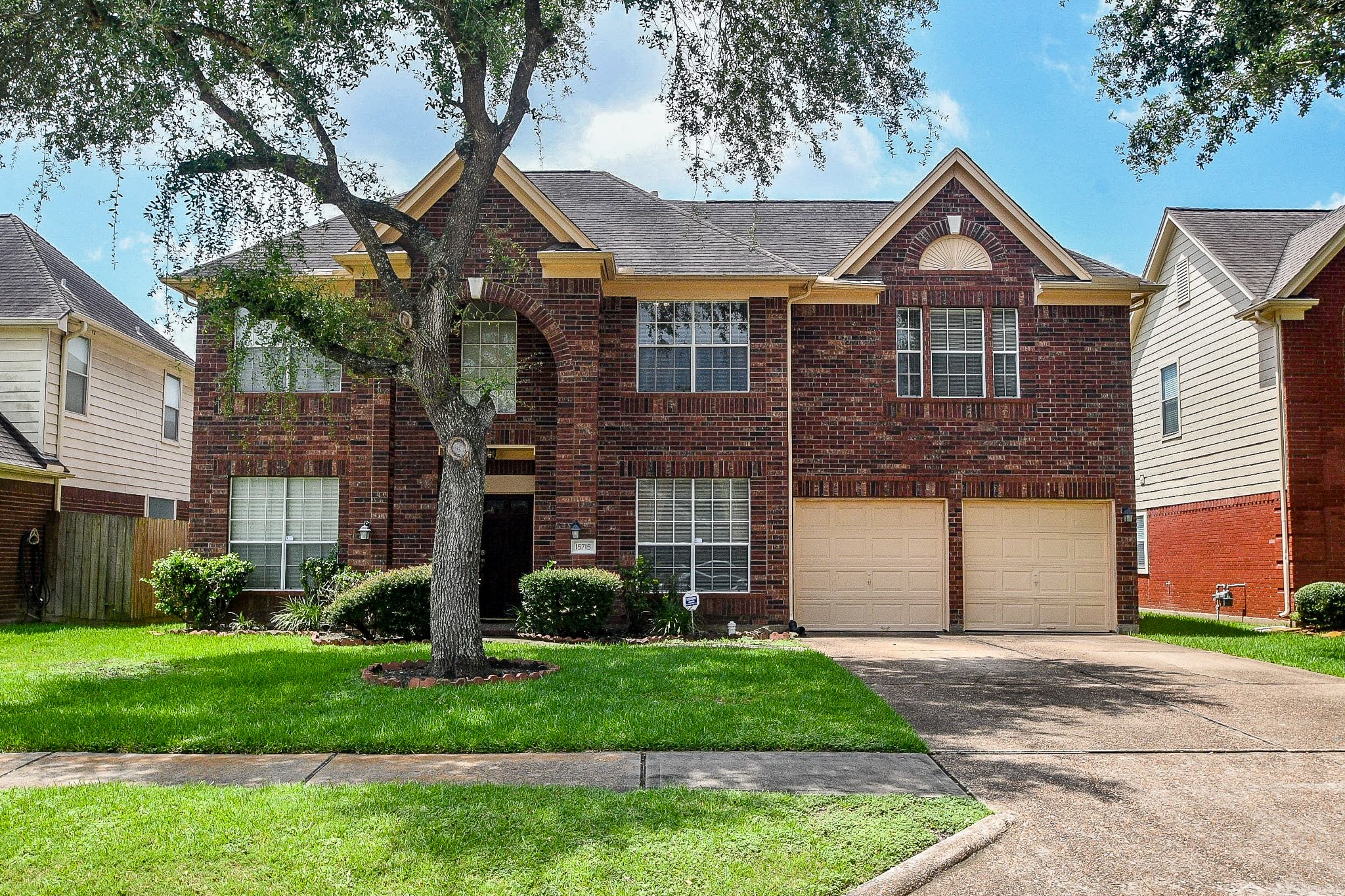 Welcome to this two-story brick home with a spacious front yard and a two-car garage. The exterior features large windows and a well-maintained lawn, with a tree adding charm to the curb appeal.