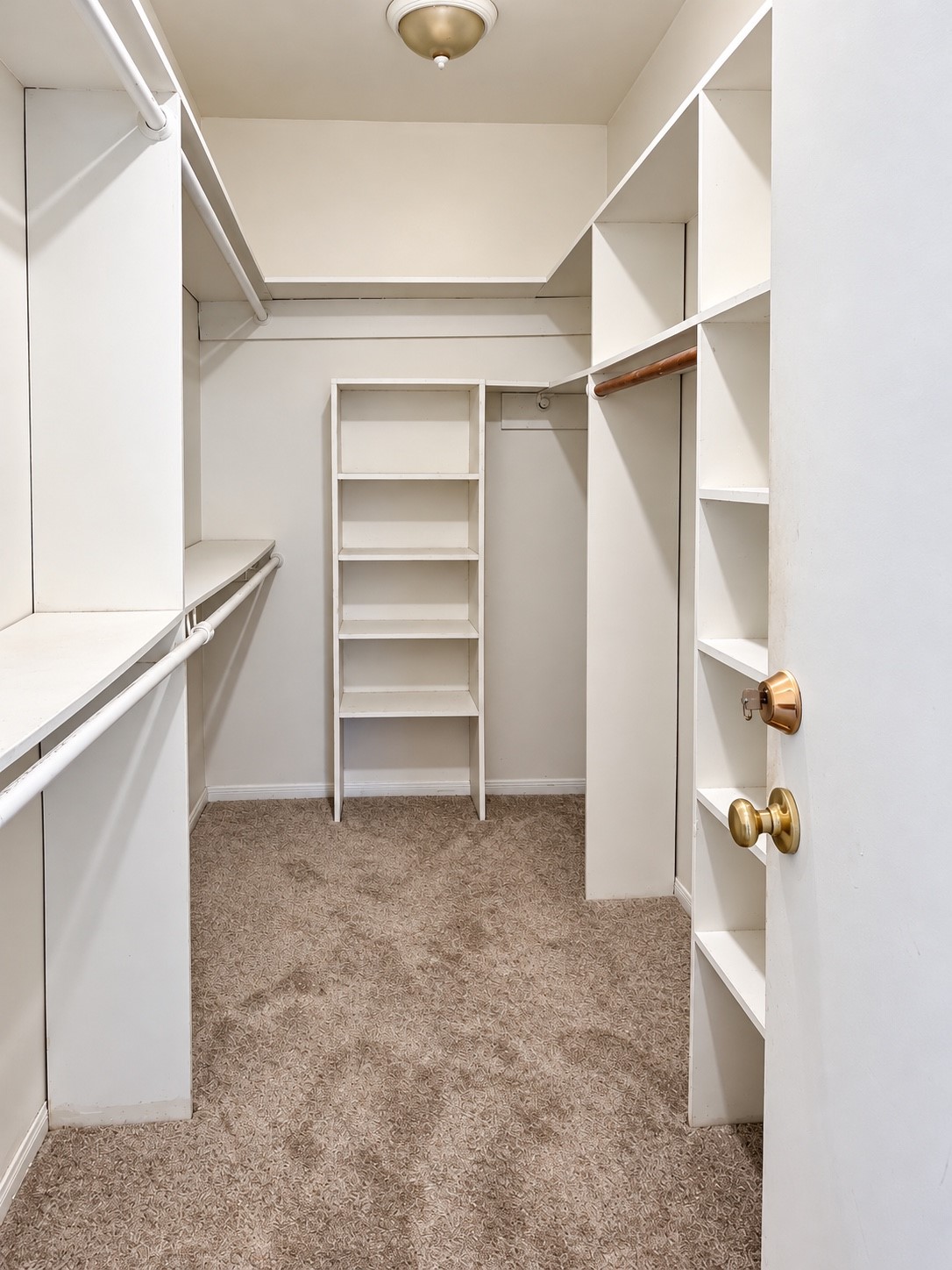 Spacious walk-in-closet with built-in shelving and multiple hanging rods for east organizing.