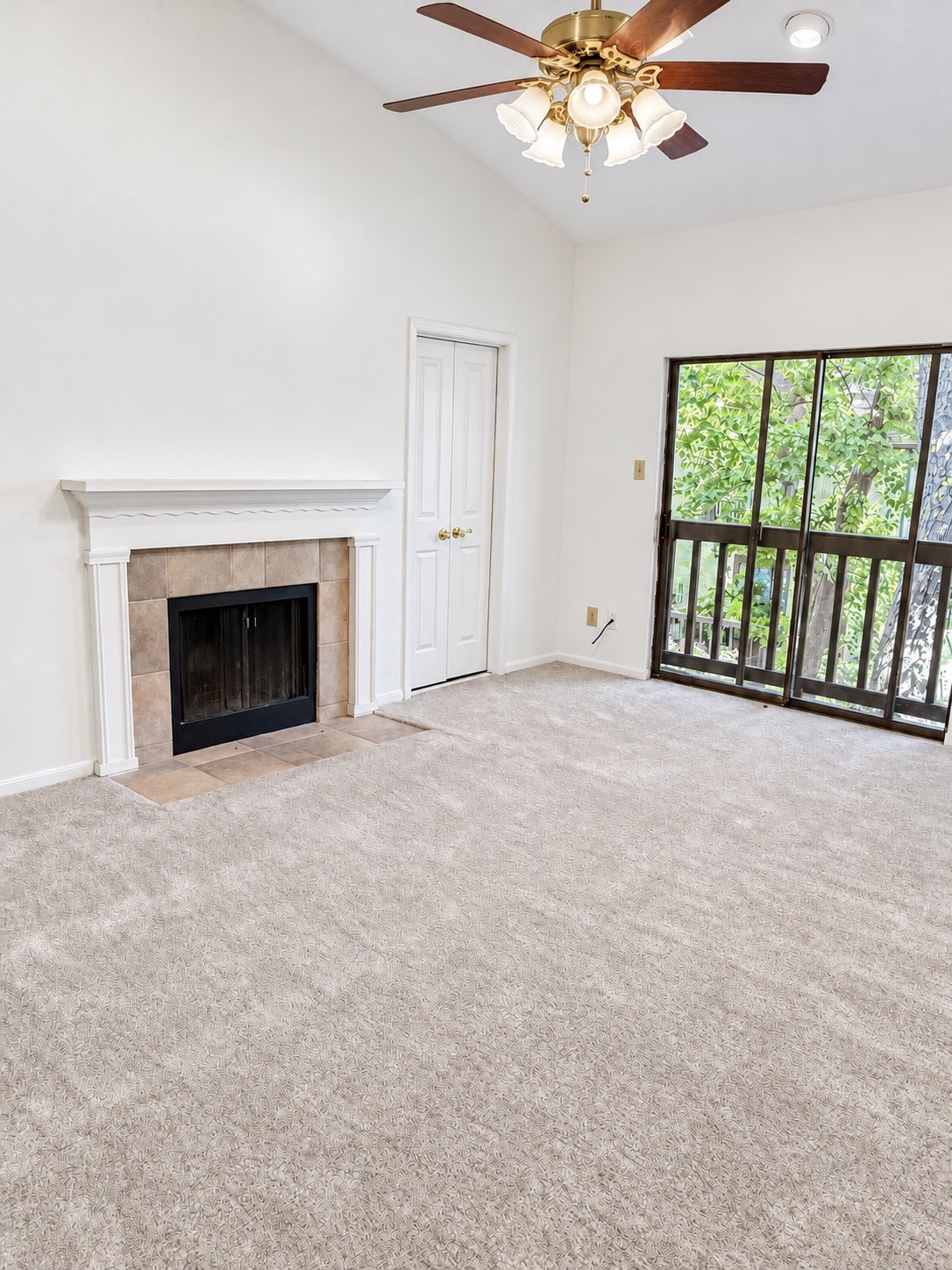 Cozy Primary Bedroom/Retreat with a fireplace, Vaulted ceiling, and sliding glass door opening to your peaceful balcony with leafy view.