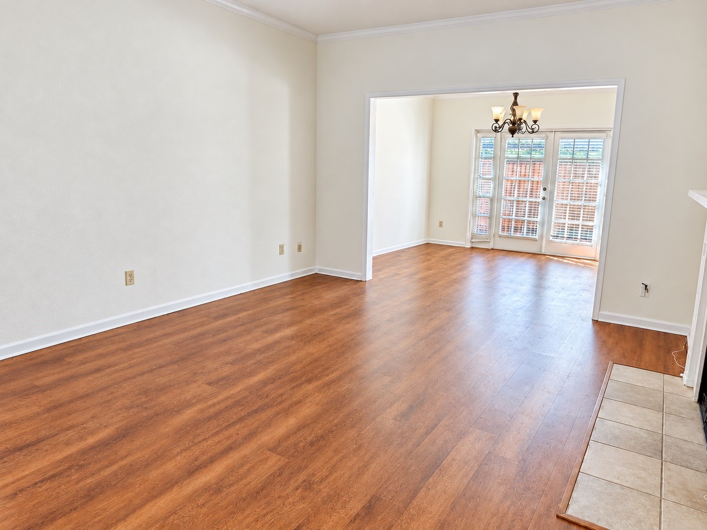 Inviting living area with wooded look flooring, crown molding, and adjoining dining space filled with natural lighting