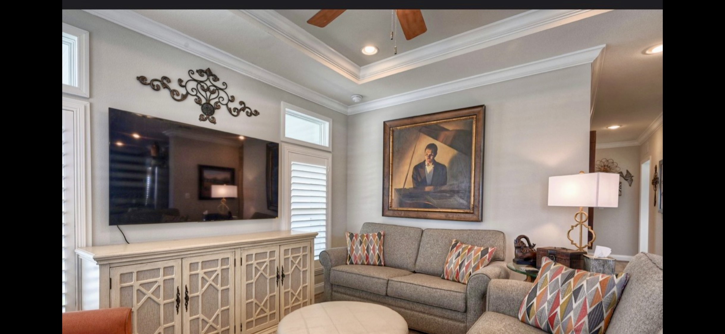 Comfortable living area features upgraded laminate flooring, crown molding & a decorative ceiling with a fan. Windows with shutters & transoms add character & natural light.