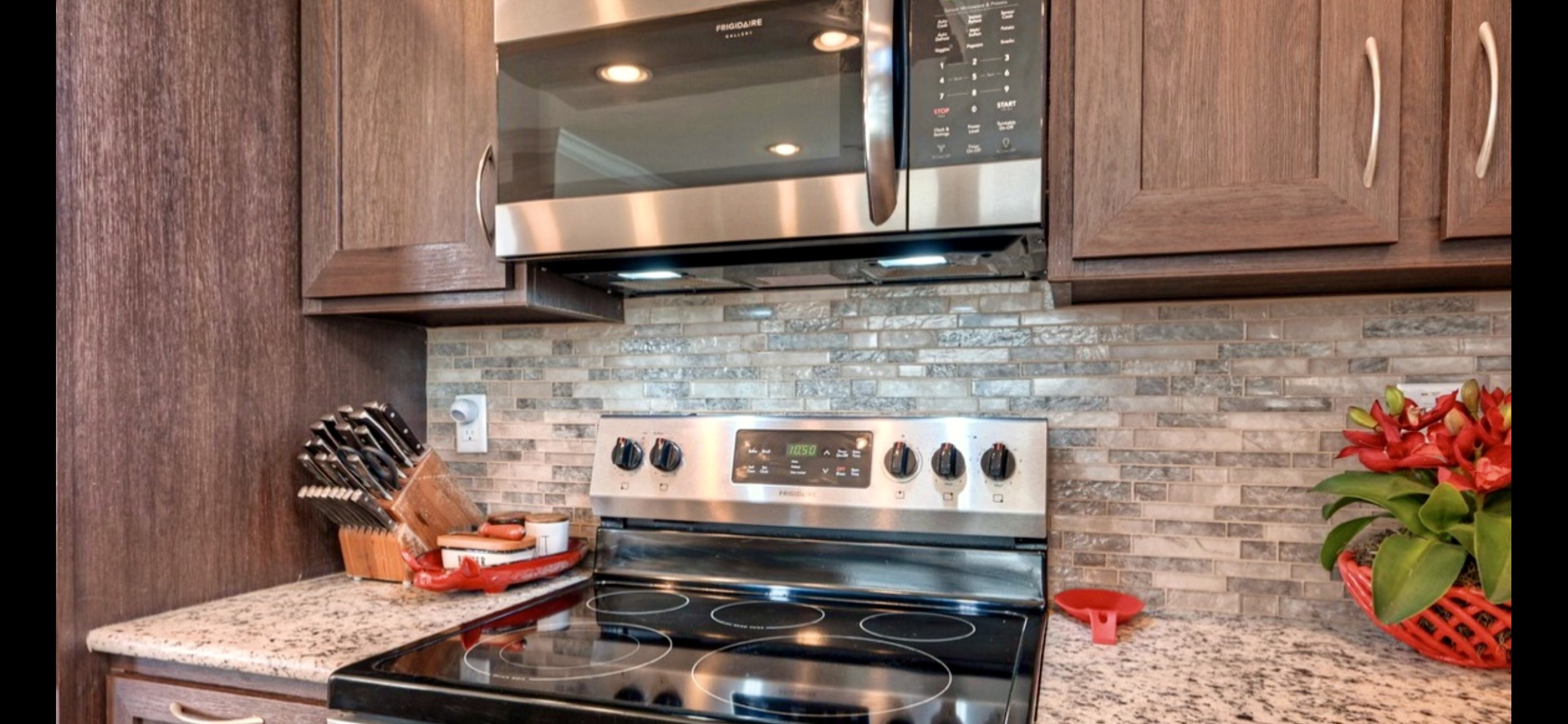 Electric range, tile backsplash & surrounding cabinetry create a practical cooking space in this inviting kitchen.