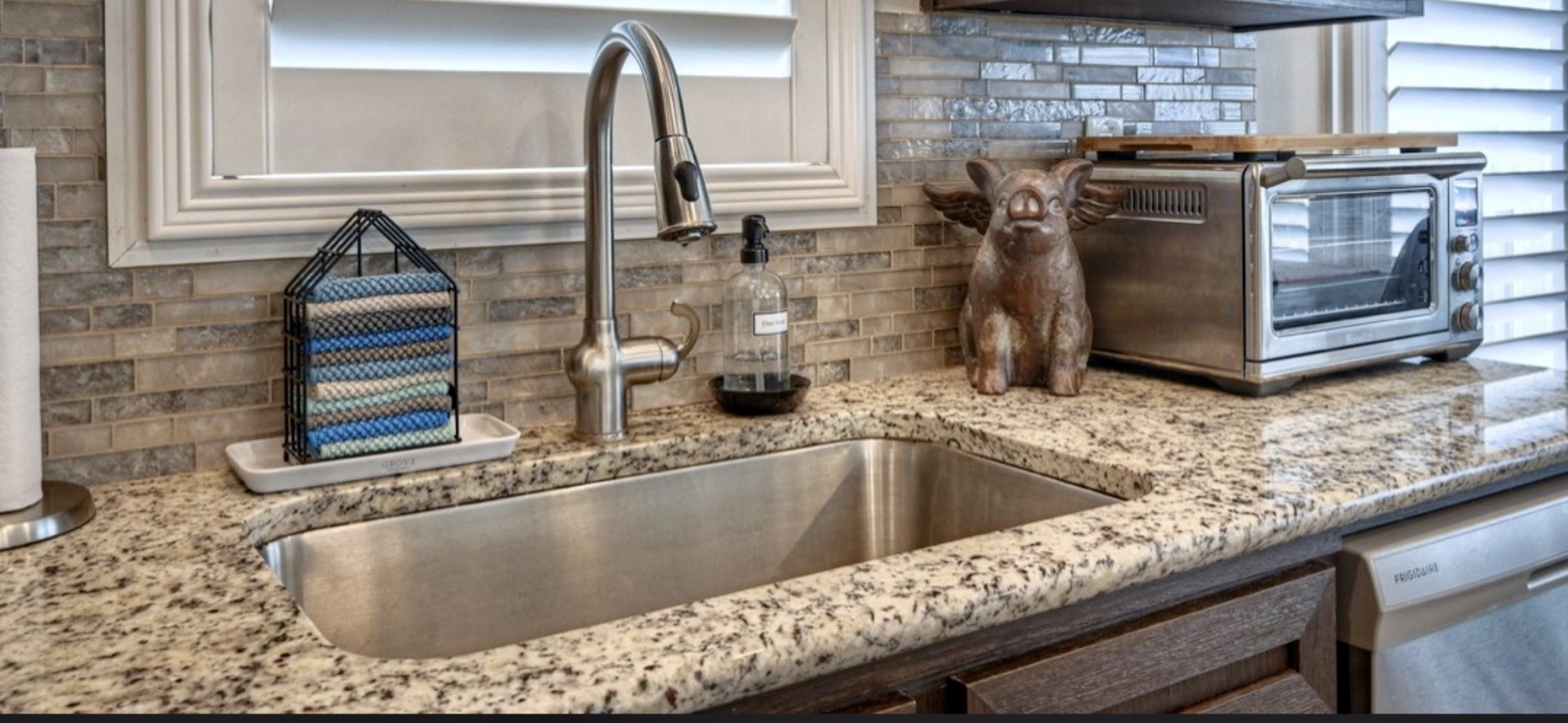 Window above the sink brings in natural light, while the tall curved faucet, surrounding counters & cabinetry offer everyday functionality.