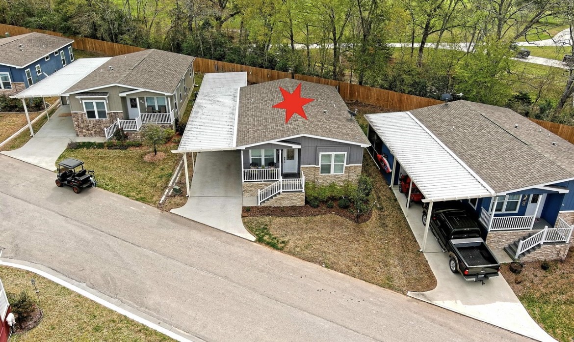 Aerial perspective showcases the home & covered parking within Thousand Trails, a community offering lake access, a boat ramp & recreational amenities. Home only; land leased.
