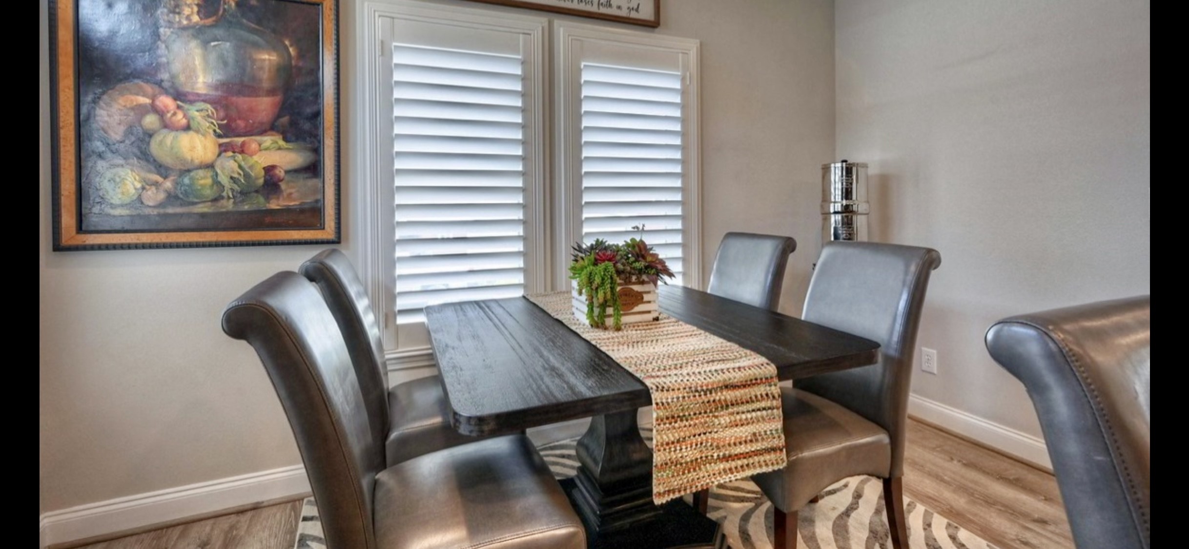 Inviting dining space sits beside shuttered windows, offering natural light & a convenient location just off the kitchen.