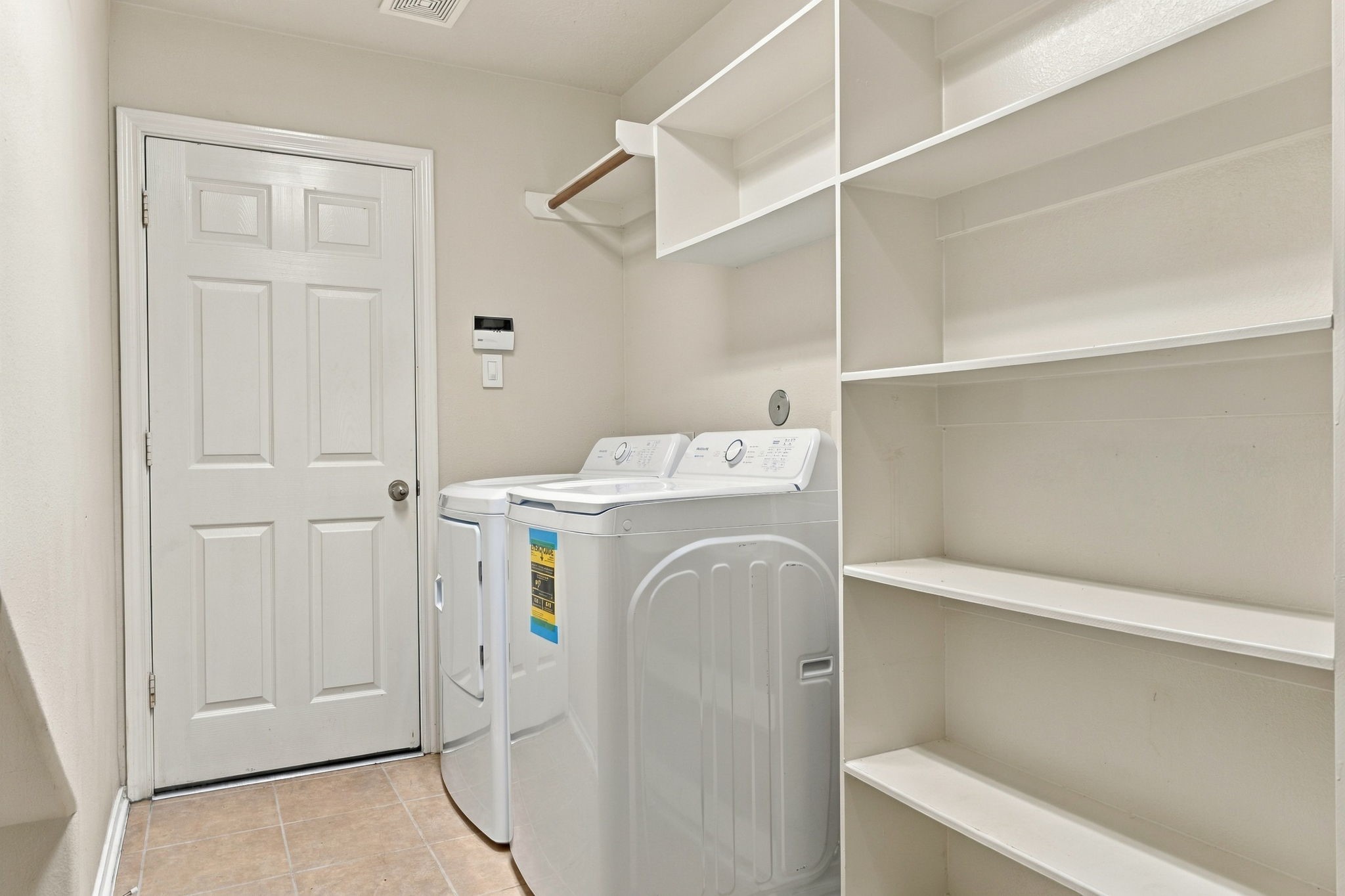 Spacious laundry room featuring modern appliances, ample shelving, and convenient storage options.