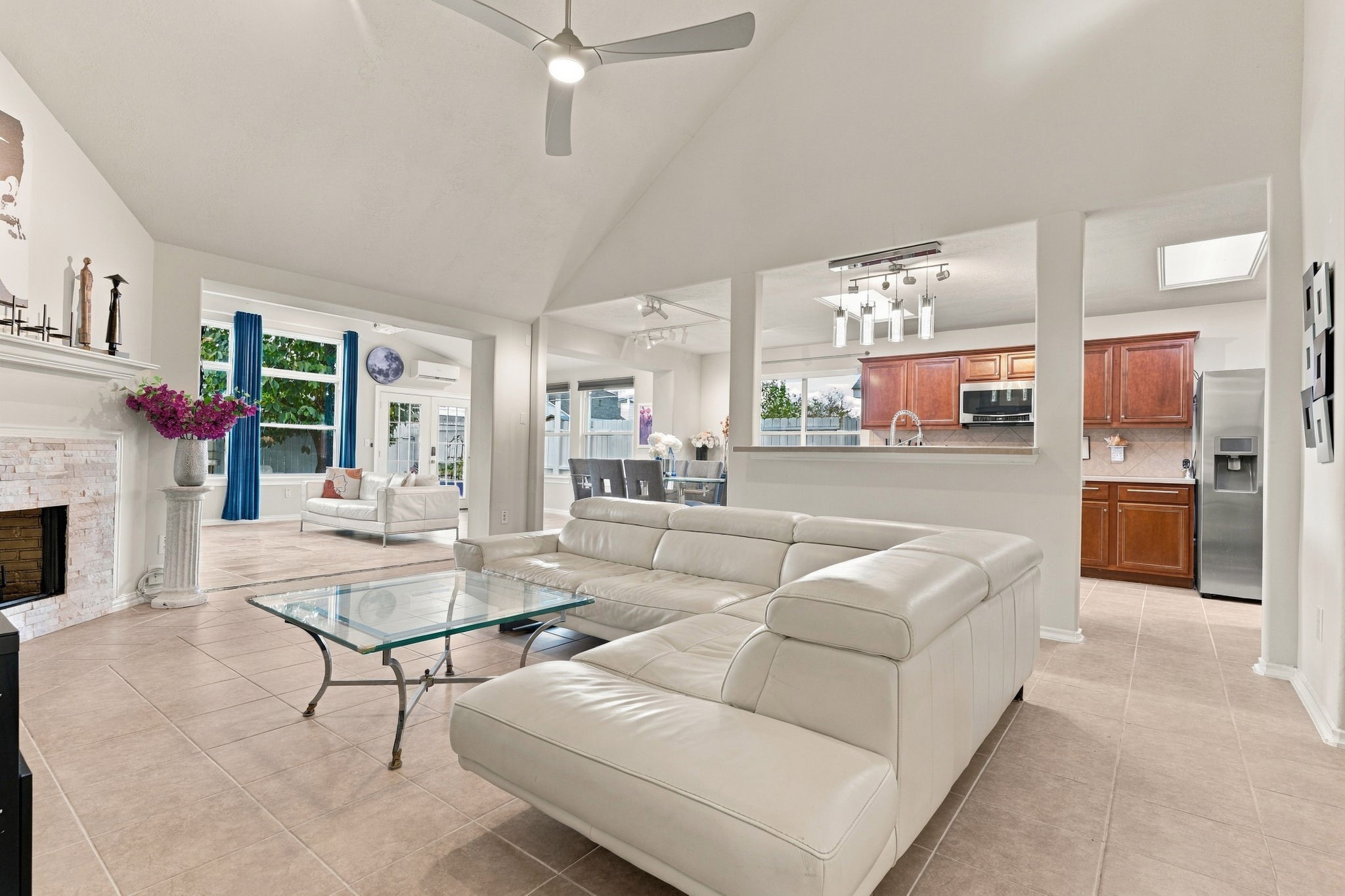 Spacious open-concept living area with vaulted ceilings, featuring a cozy fireplace, modern kitchen, and ample natural light.