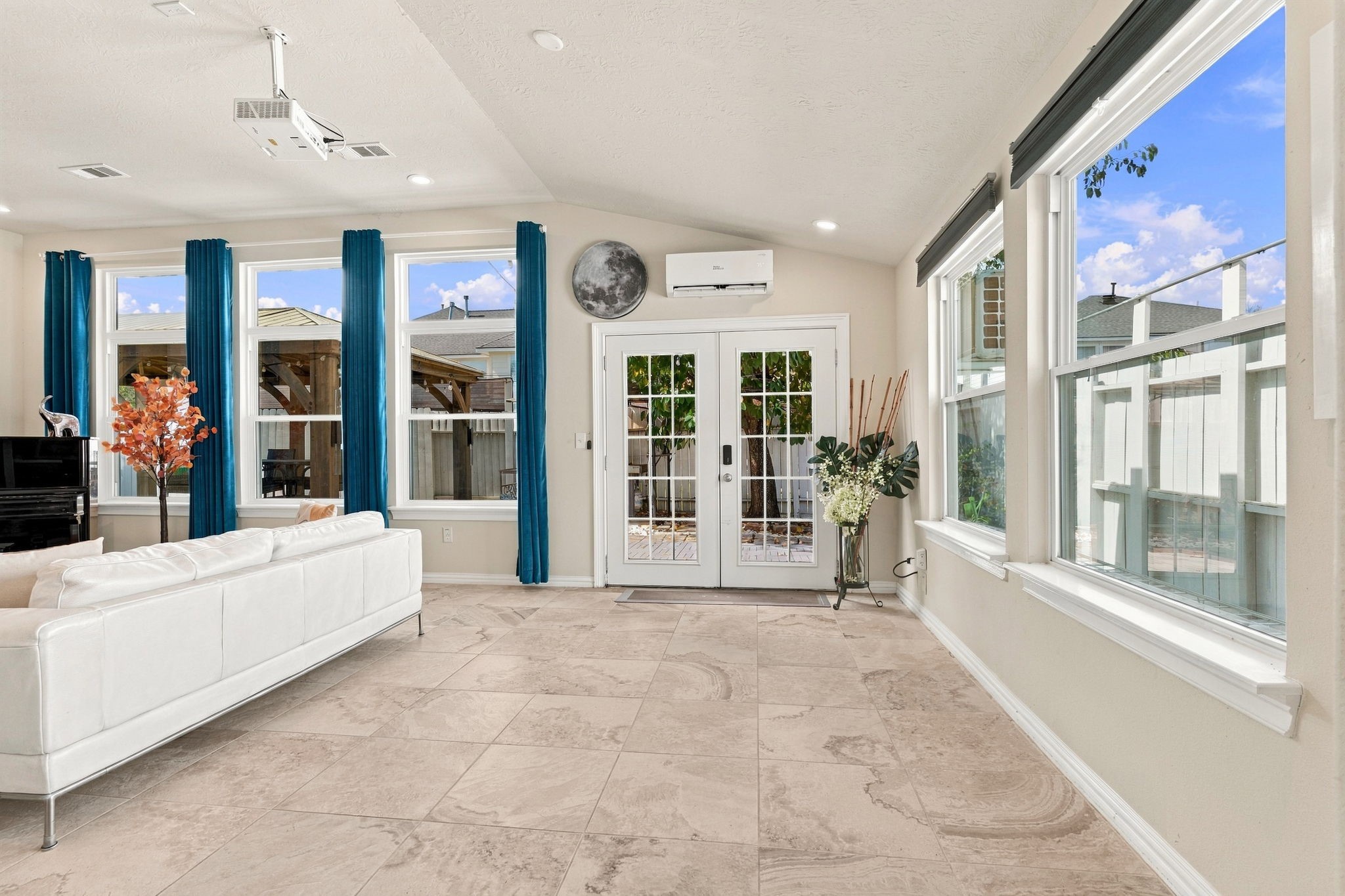 Bright and inviting living space with large windows, natural light, and elegant tile flooring, perfect for relaxation and entertaining.