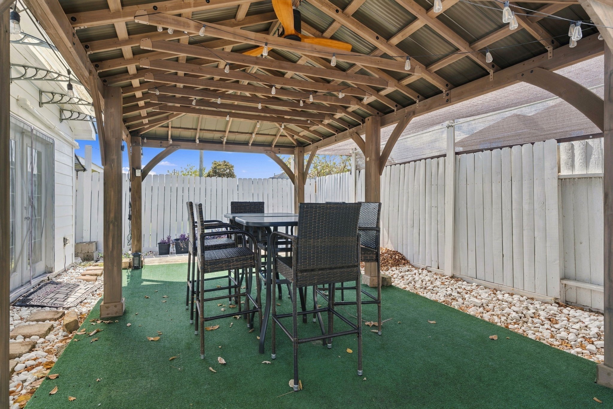 Charming outdoor space featuring a covered pergola with string lights, perfect for entertaining or relaxing in a private, fenced yard.
