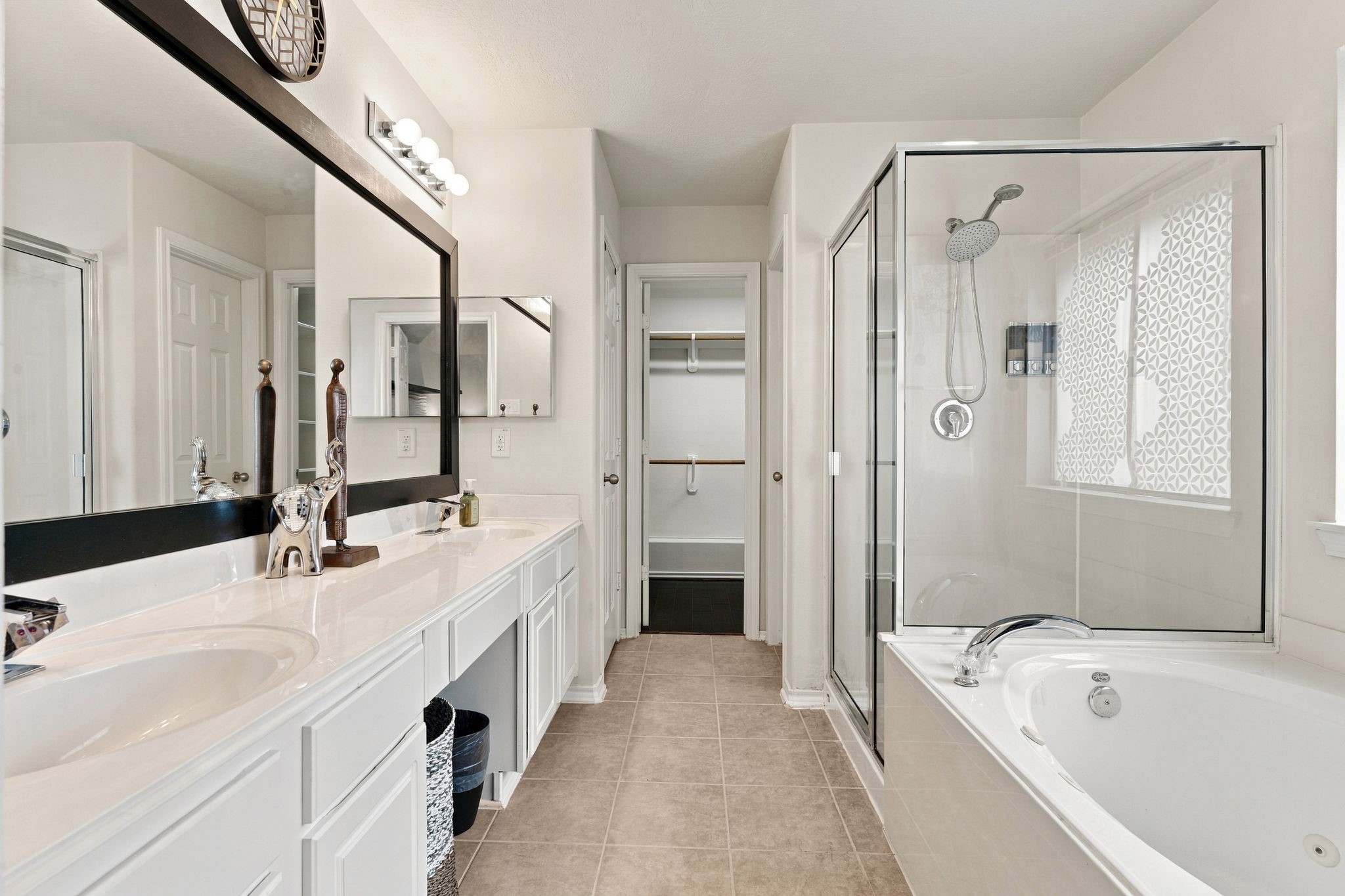 Spacious and elegant bathroom featuring a dual-sink vanity, a glass-enclosed shower, and a luxurious soaking tub, complemented by ample natural light and modern fixtures.