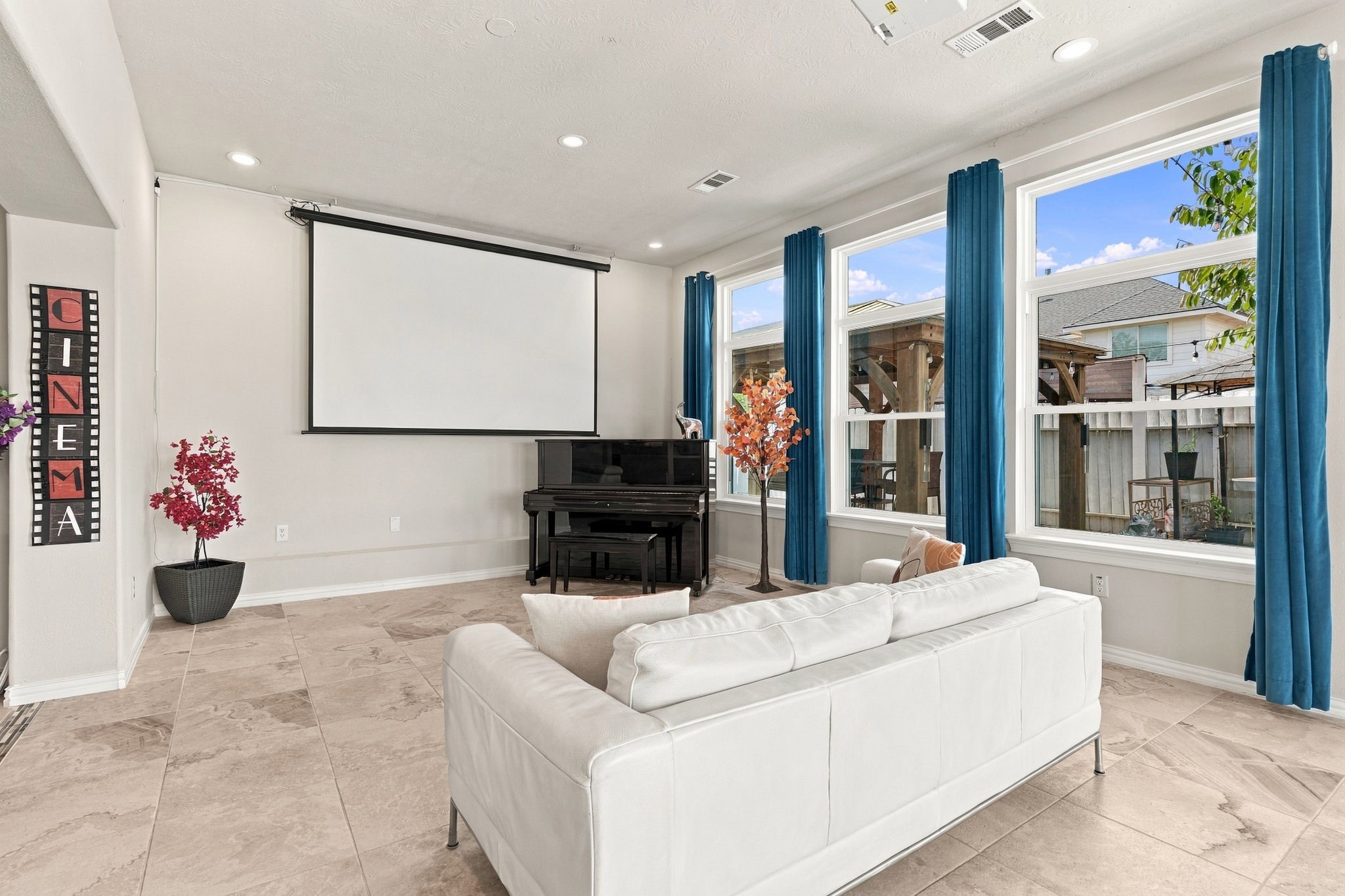 Spacious home theater room with large windows, a sleek white sofa, and a grand piano, perfect for entertainment and relaxation. (Projector and Screen included) (Furniture not included)