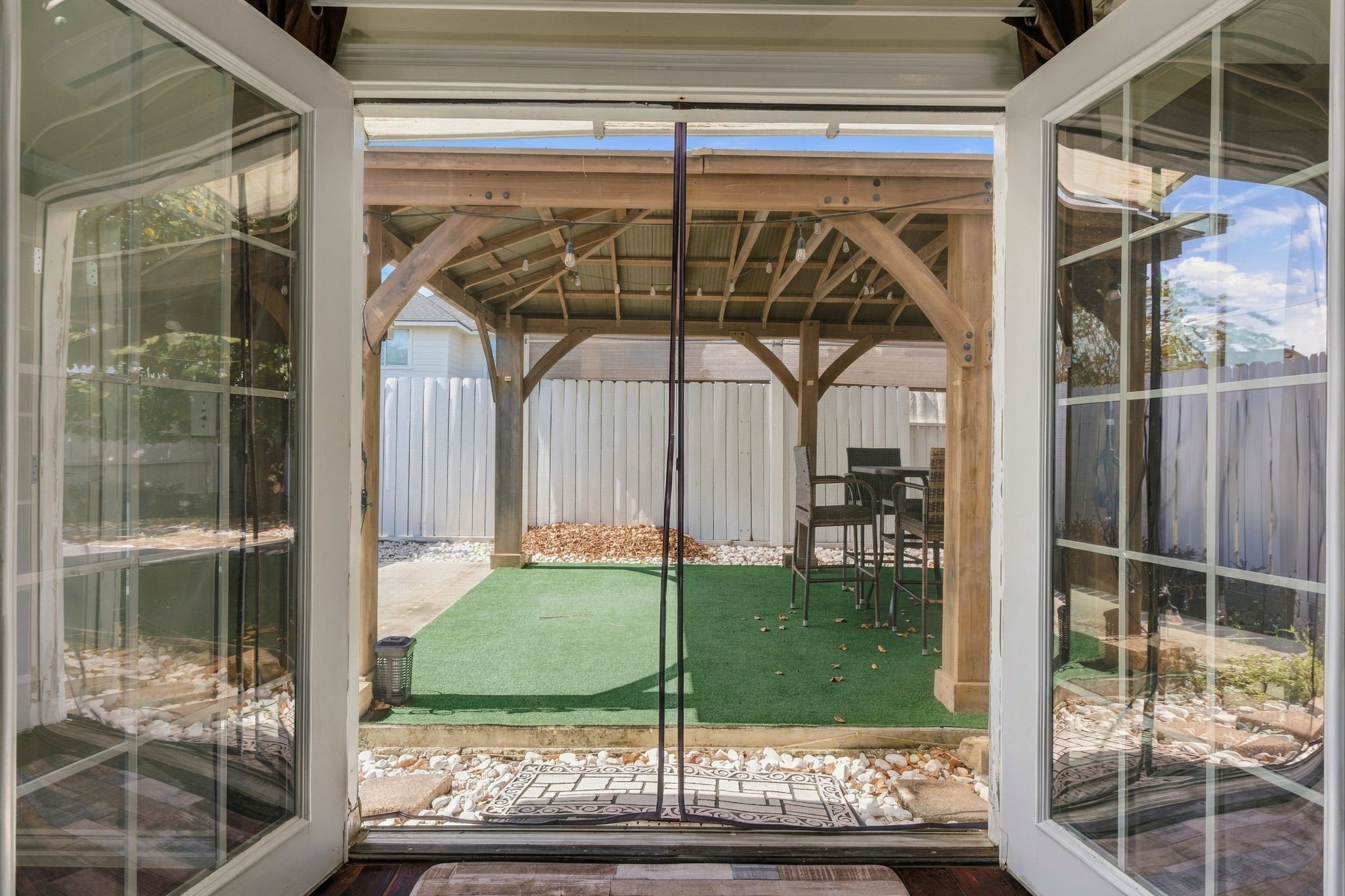 Step into your private oasis through elegant French doors, leading to a cozy backyard retreat featuring a charming pergola and lush artificial turf, perfect for outdoor relaxation and entertaining.