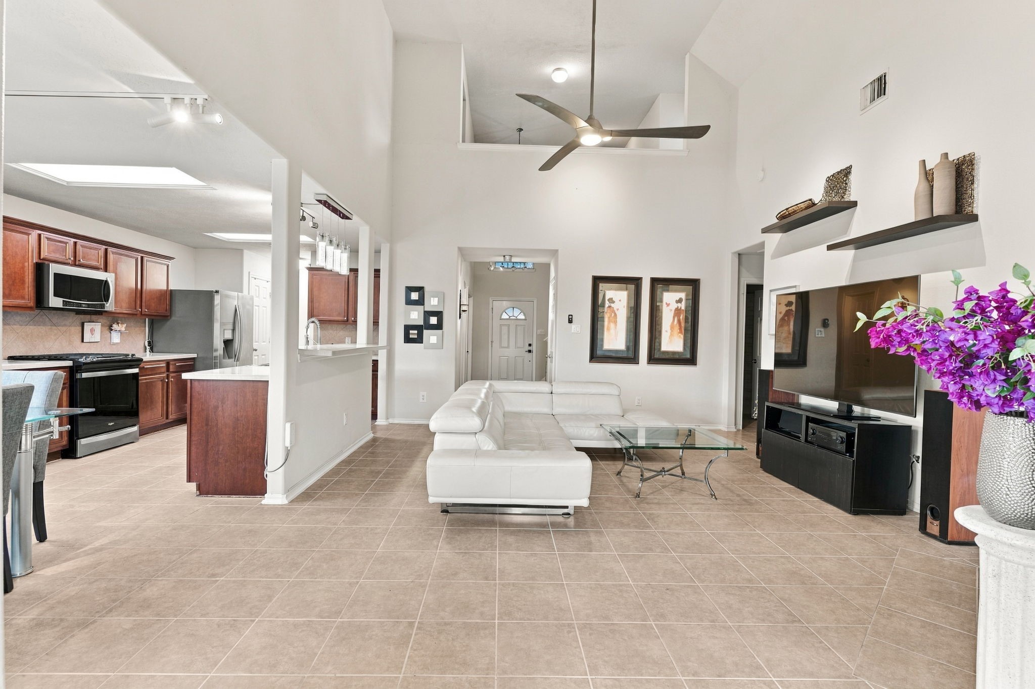 Spacious open-concept living area featuring vaulted ceilings, modern finishes, and an abundance of natural light, seamlessly connecting to a stylish kitchen with rich cabinetry and stainless steel appliances.