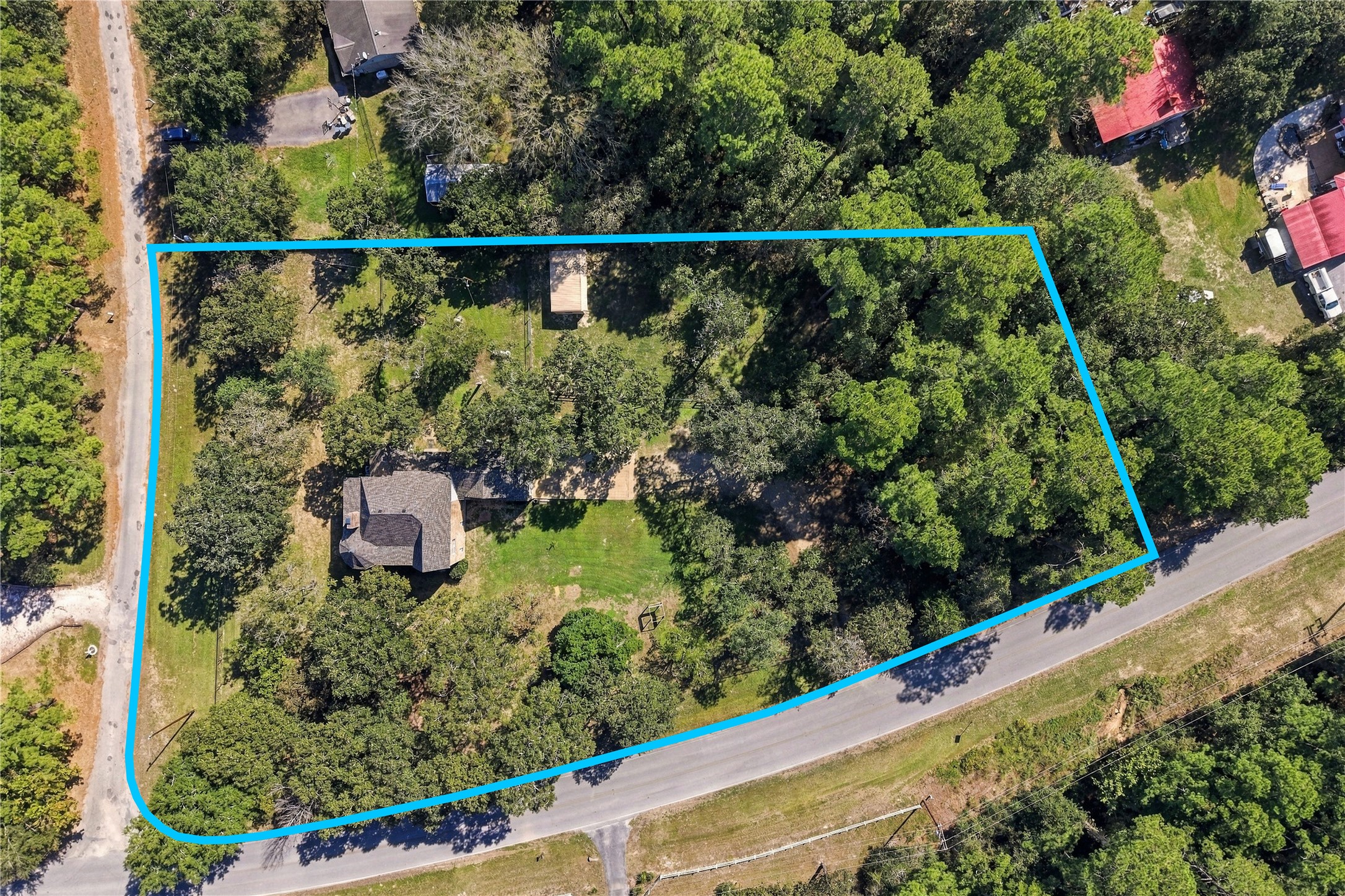 Aerial view highlighting the property's wooded setting, home, outdoor improvements, and approximate property boundaries. *Property lines shown are approximate and for illustrative purposes only. Not a survey. Buyer to independently verify property boundaries.