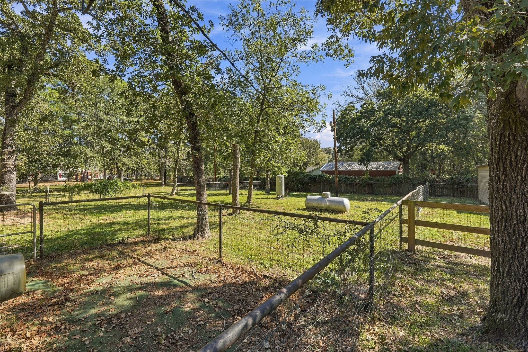 Additional fenced areas provide versatile outdoor space with mature trees and room for a variety of uses.