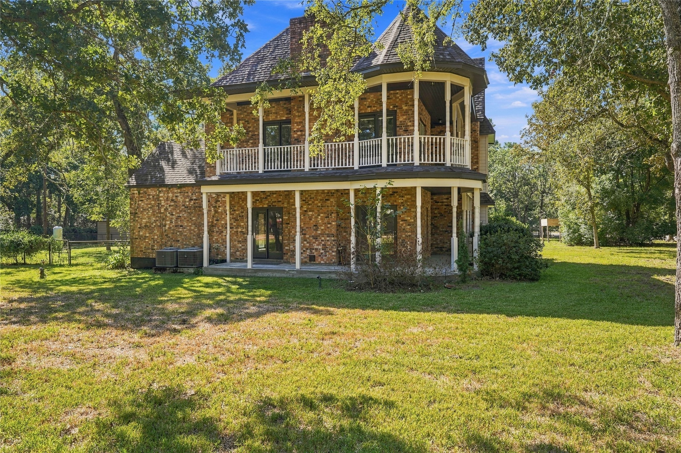 Charming two-story home with covered lower patio and upper-level balcony overlooking the spacious, wooded grounds.