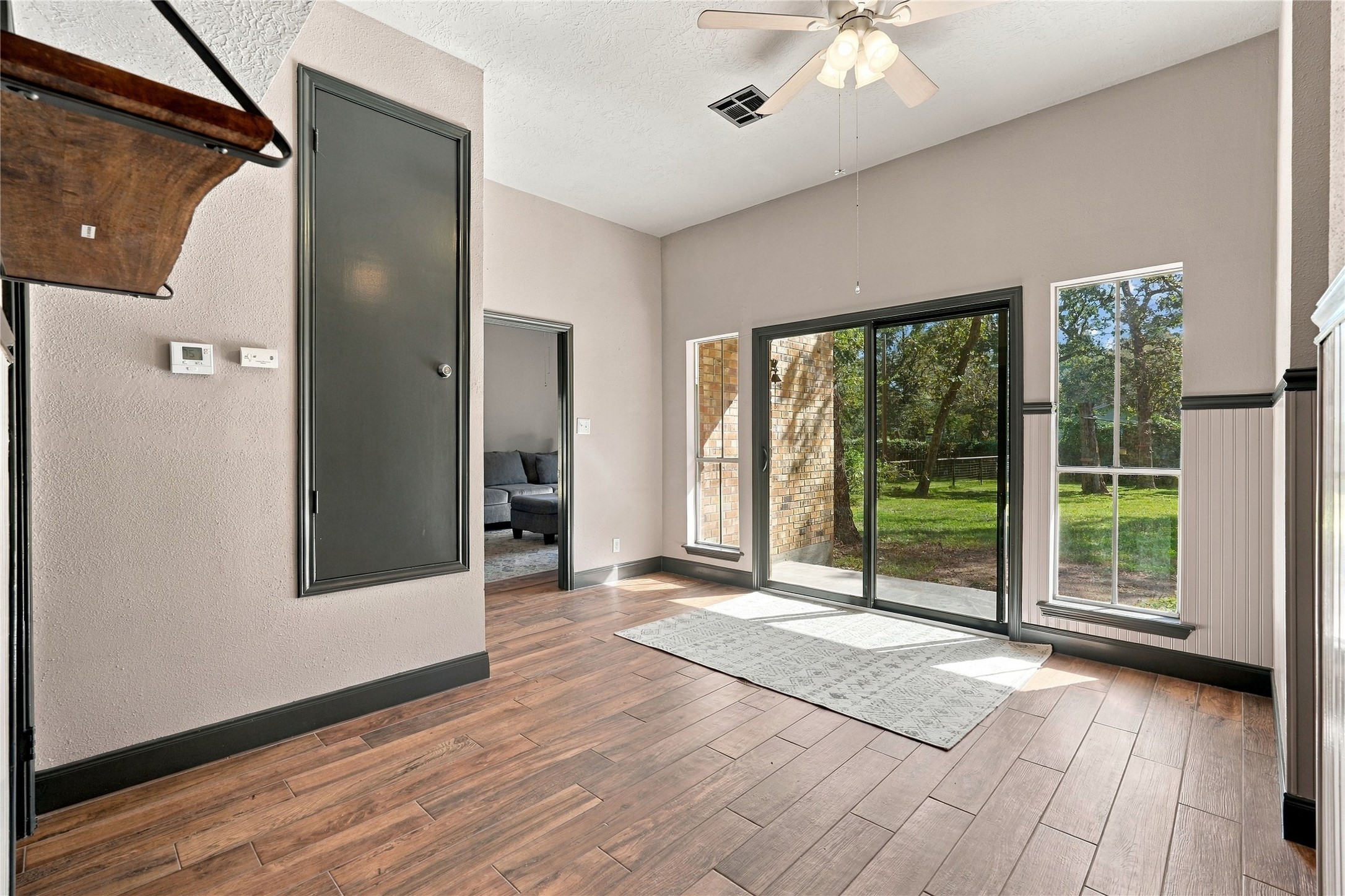 View from the kitchen into the breakfast room, featuring wood-look flooring, abundant natural light, and convenient access to the adjoining family room.