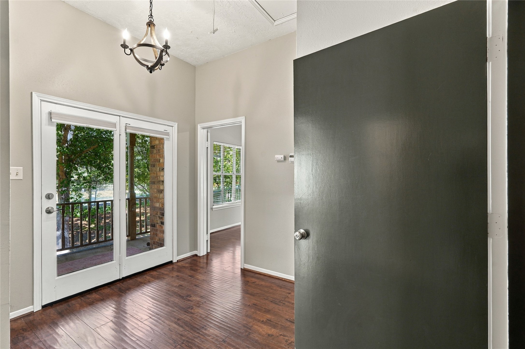 Upstairs landing with wood flooring, high ceilings, and French doors leading to the covered second-floor balcony.