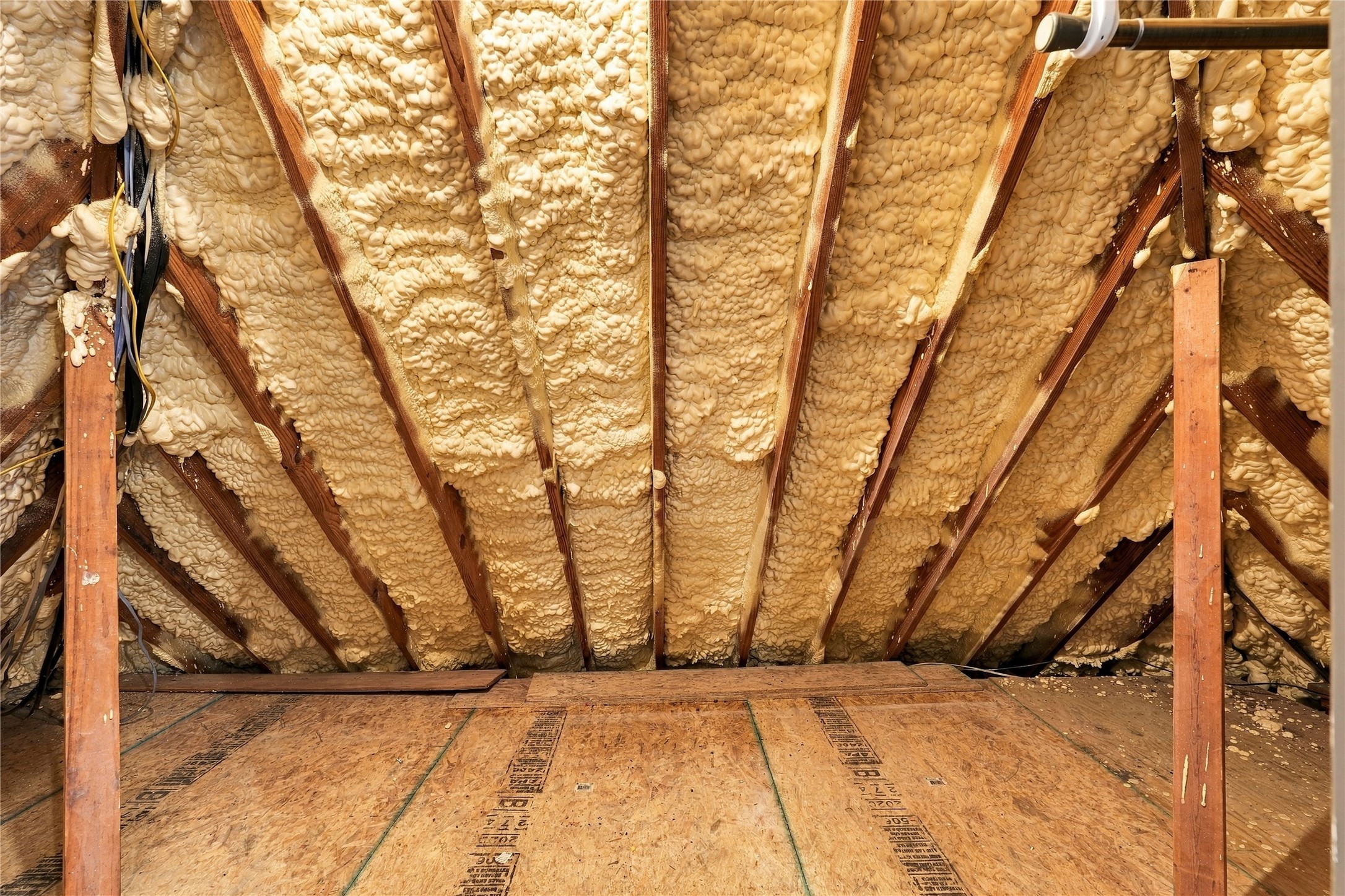Attic storage area featuring spray foam insulation and wood decking for additional storage.