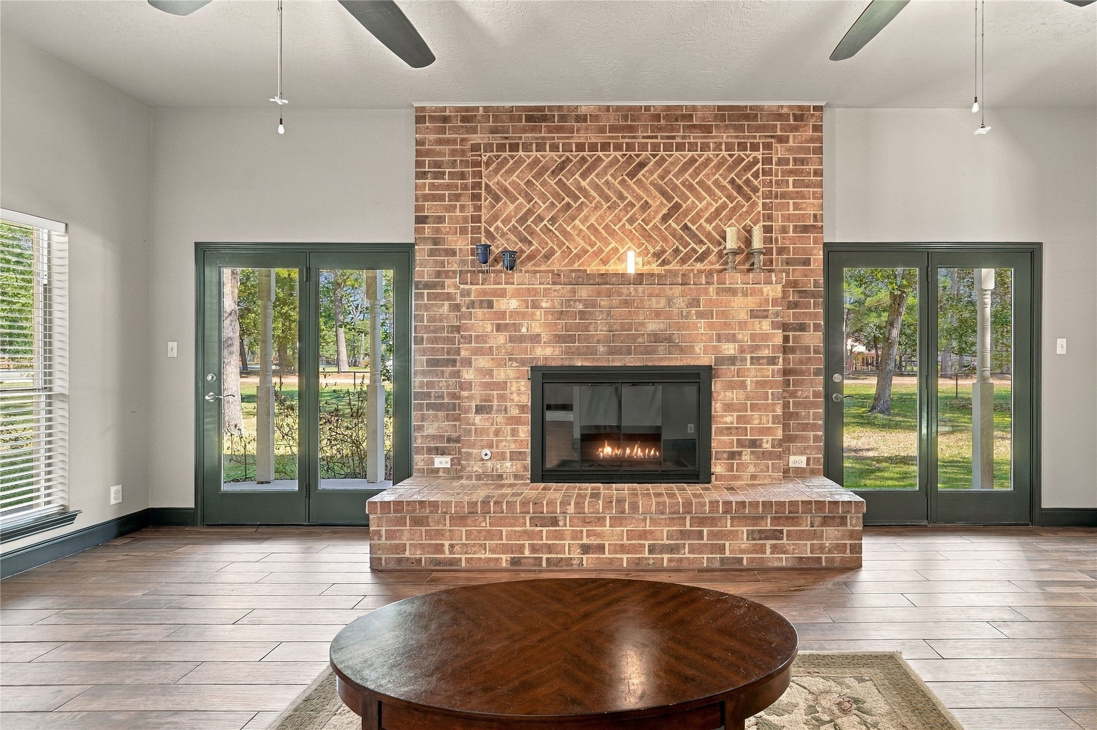 Floor-to-ceiling brick fireplace serves as the focal point of the living room, flanked by glass doors offering natural light and outdoor access.