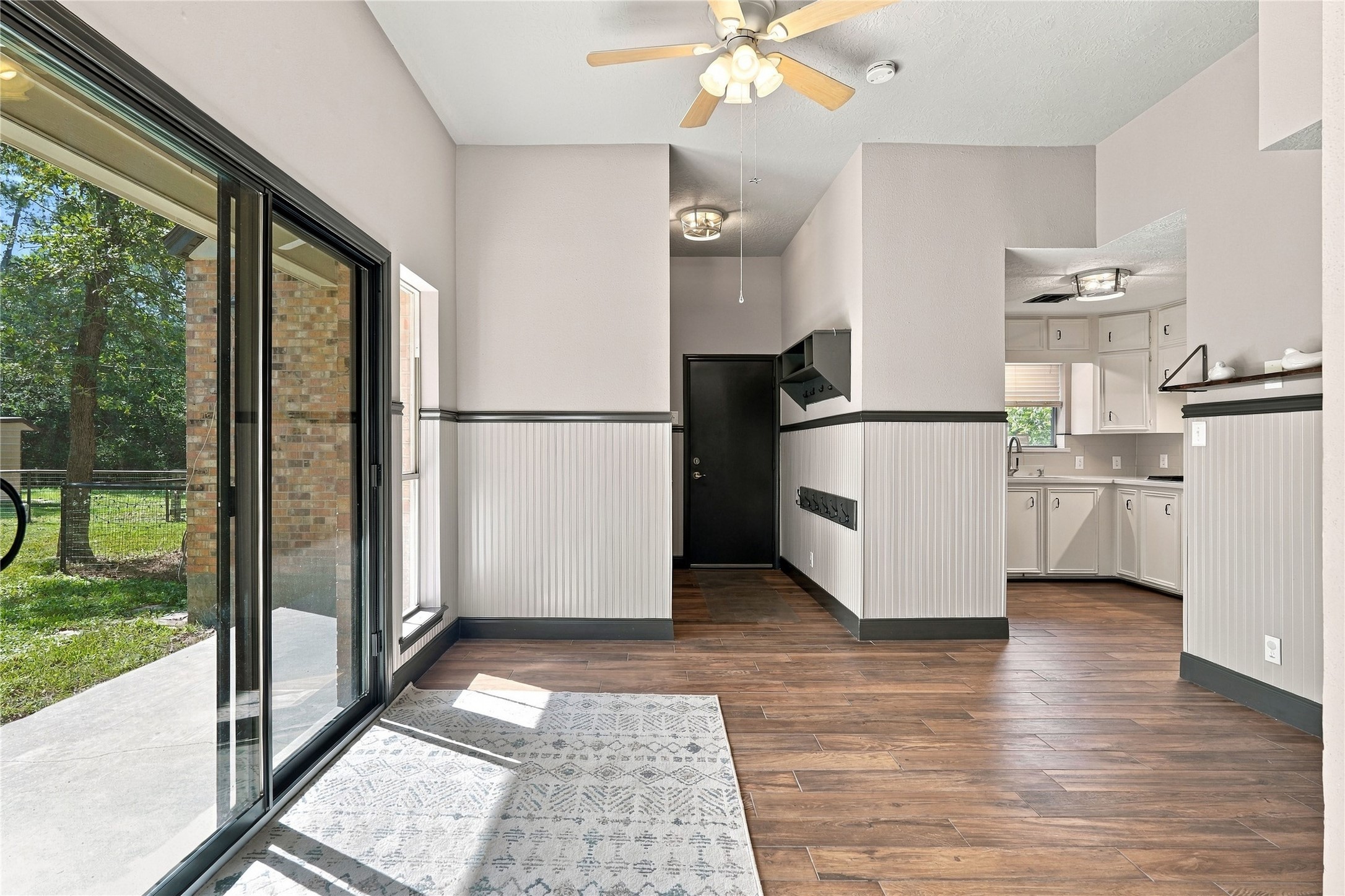 Spacious breakfast area featuring wood-look flooring, decorative wainscoting, and sliding glass doors opening to the backyard patio.