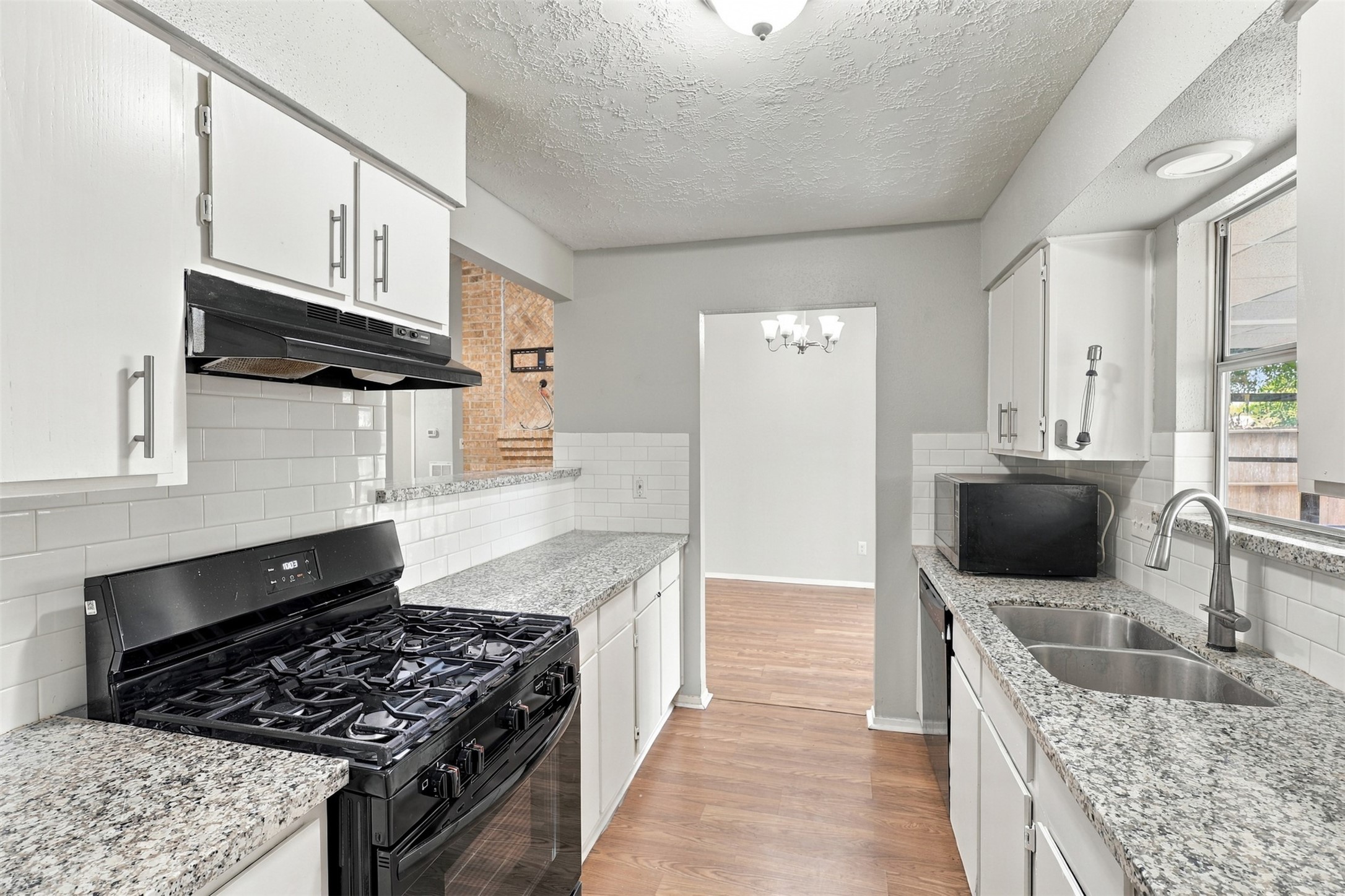 An alternate kitchen view highlights the gas range, granite work surfaces, and upper and lower cabinet storage.
