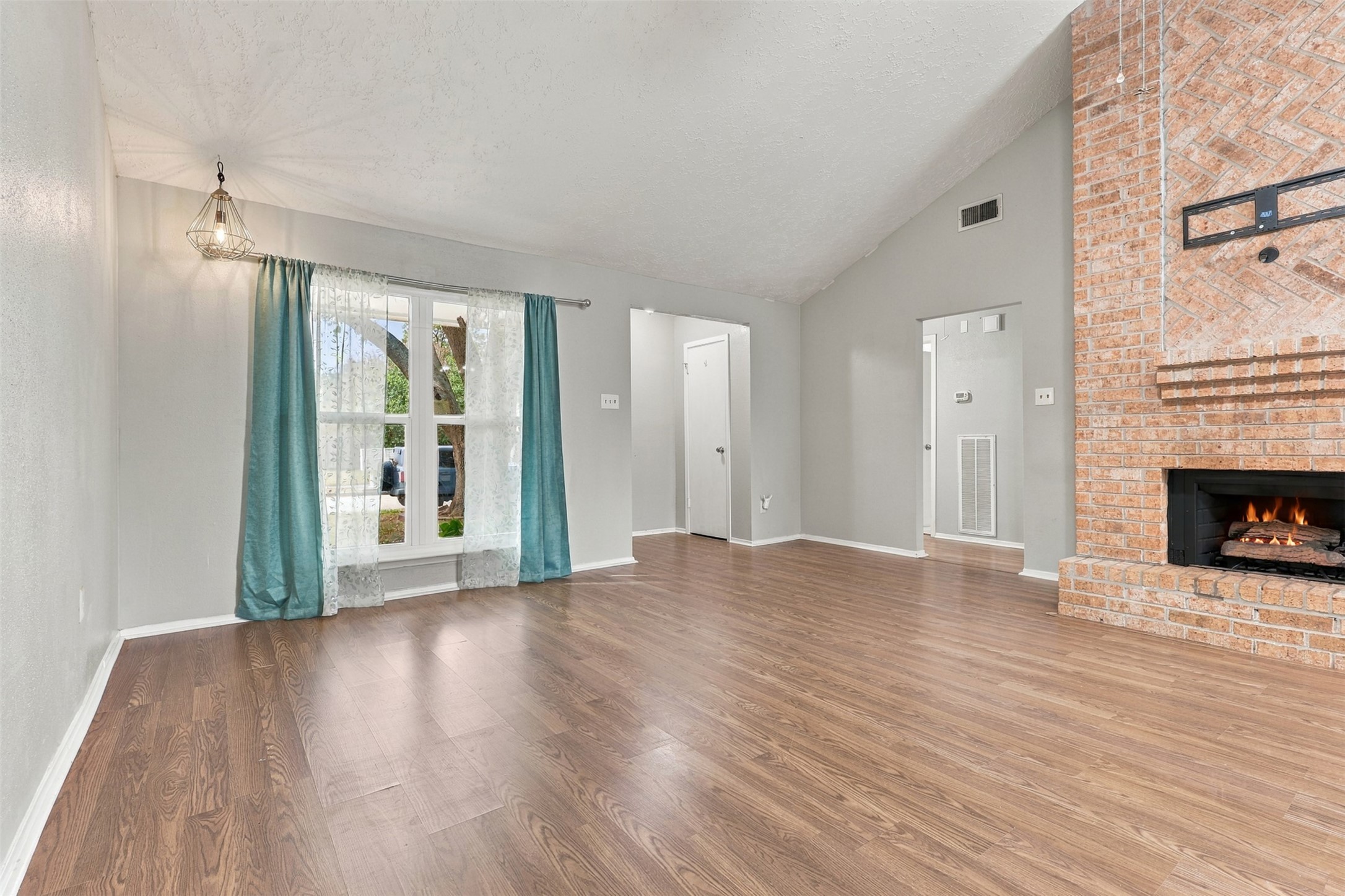 Generous living area offers flexible furniture arrangements, with a vaulted ceiling and large window that welcome natural light.
