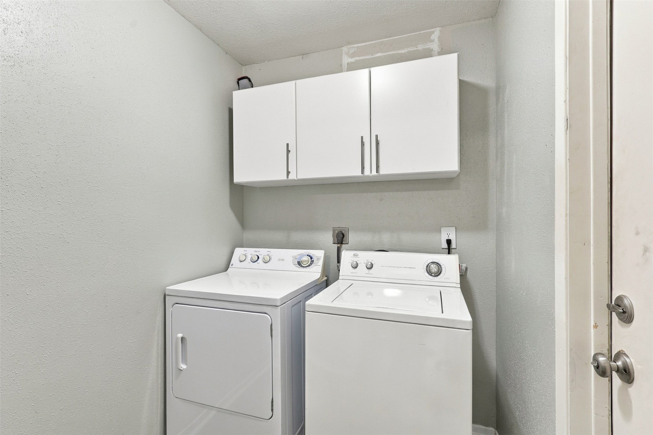 Dedicated laundry area includes overhead cabinetry to keep laundry supplies organized and within reach.