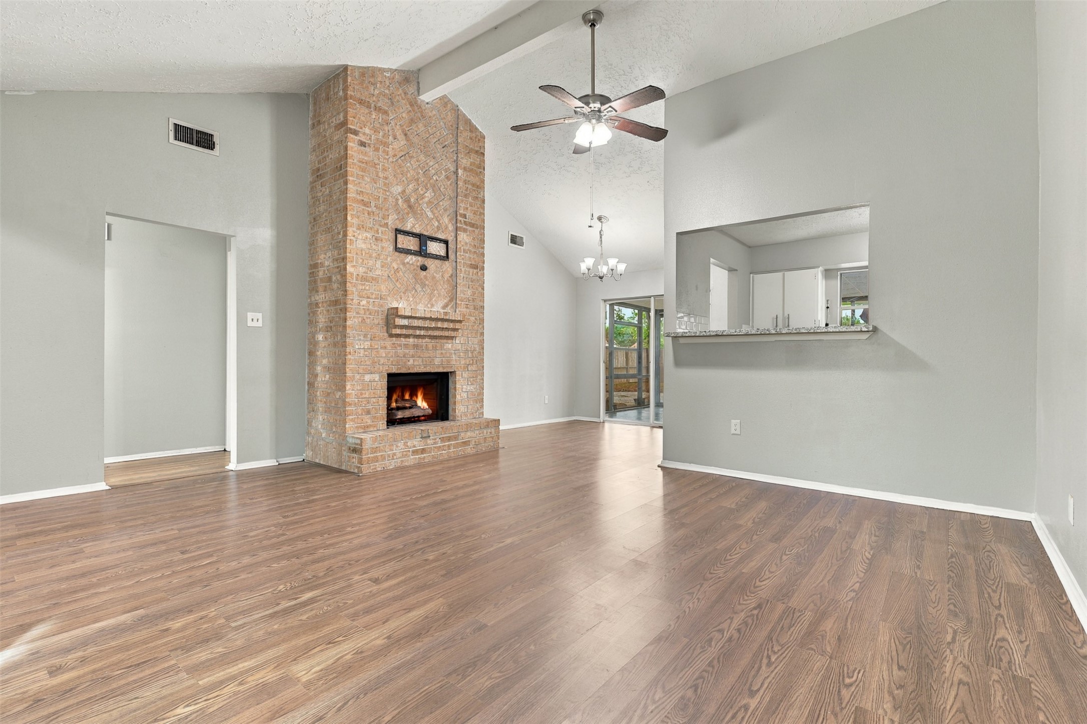 A floor-to-ceiling brick gas fireplace anchors the living room, while the kitchen pass-through keeps the spaces connected.