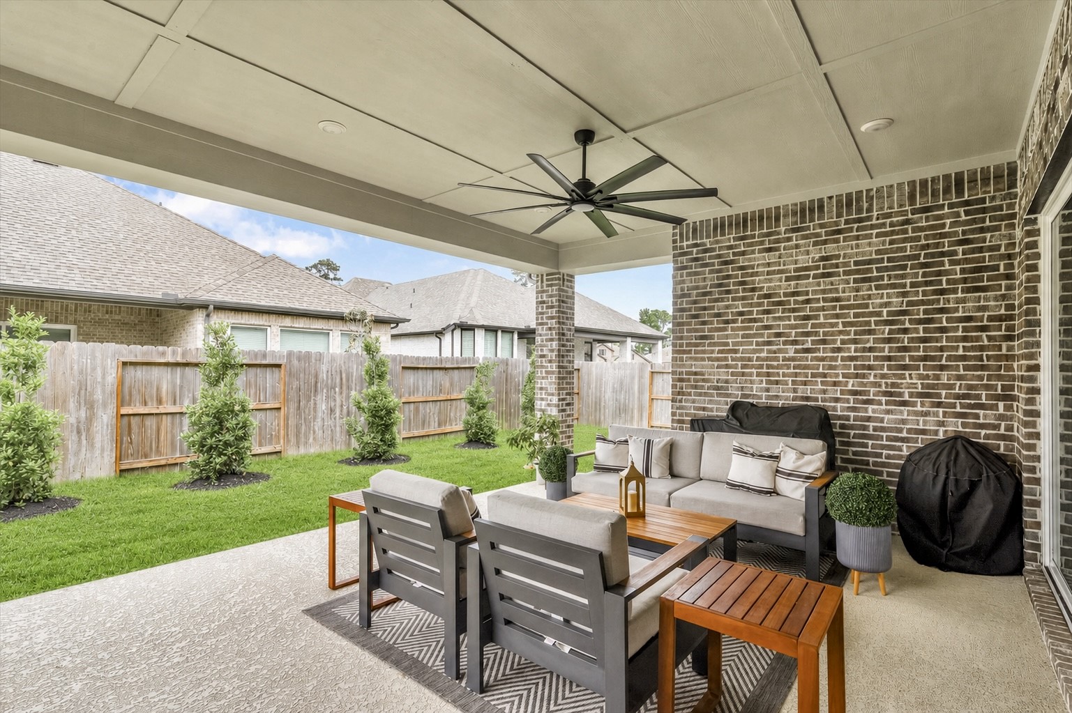 cozy covered patio with enough space for comfortable seating, ceiling fan, and well-maintained backyard with privacy perfect for outdoor relaxation and entertaining.