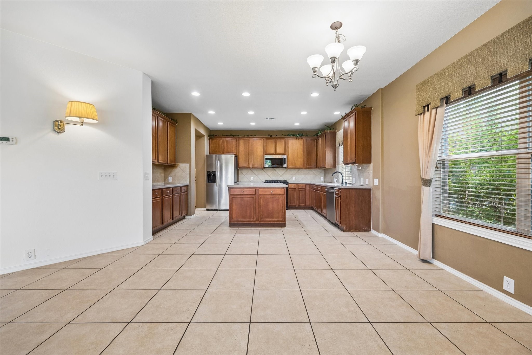 Spacious kitchen with elegant wood cabinetry, stainless steel appliances, and ample natural light from large windows.