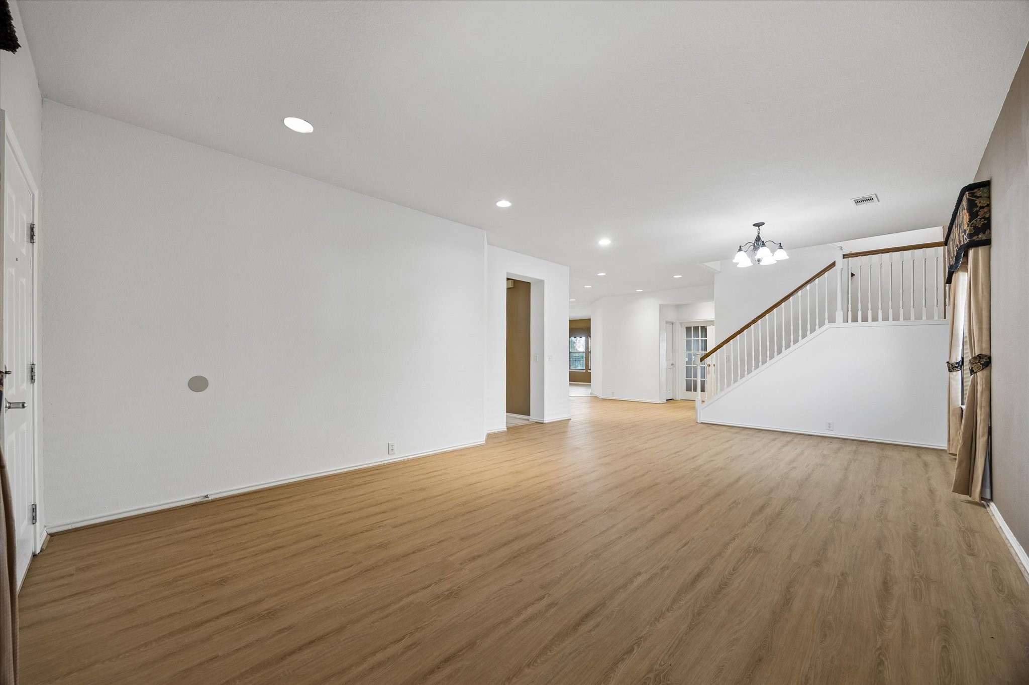 Upon entering you will be greeted by a spacious open-concept living area with elegant wood flooring and recessed lighting, featuring a staircase leading to the upper level.