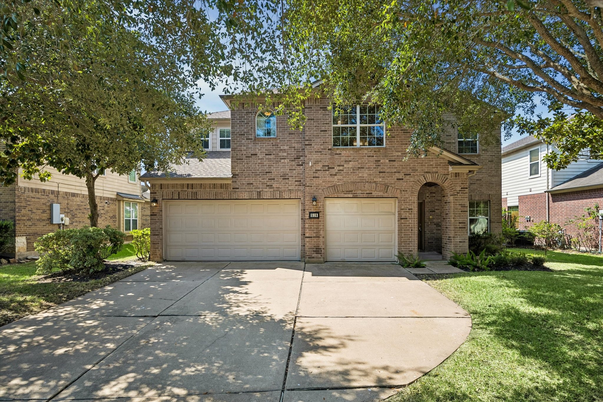 Charming two-story brick home with a spacious three-car garage, nestled among mature trees, offering ample driveway space and lush green landscaping. Charming two-story brick home with a spacious three-car garage, nestled among mature trees, offering ample driveway space and lush green landscaping.