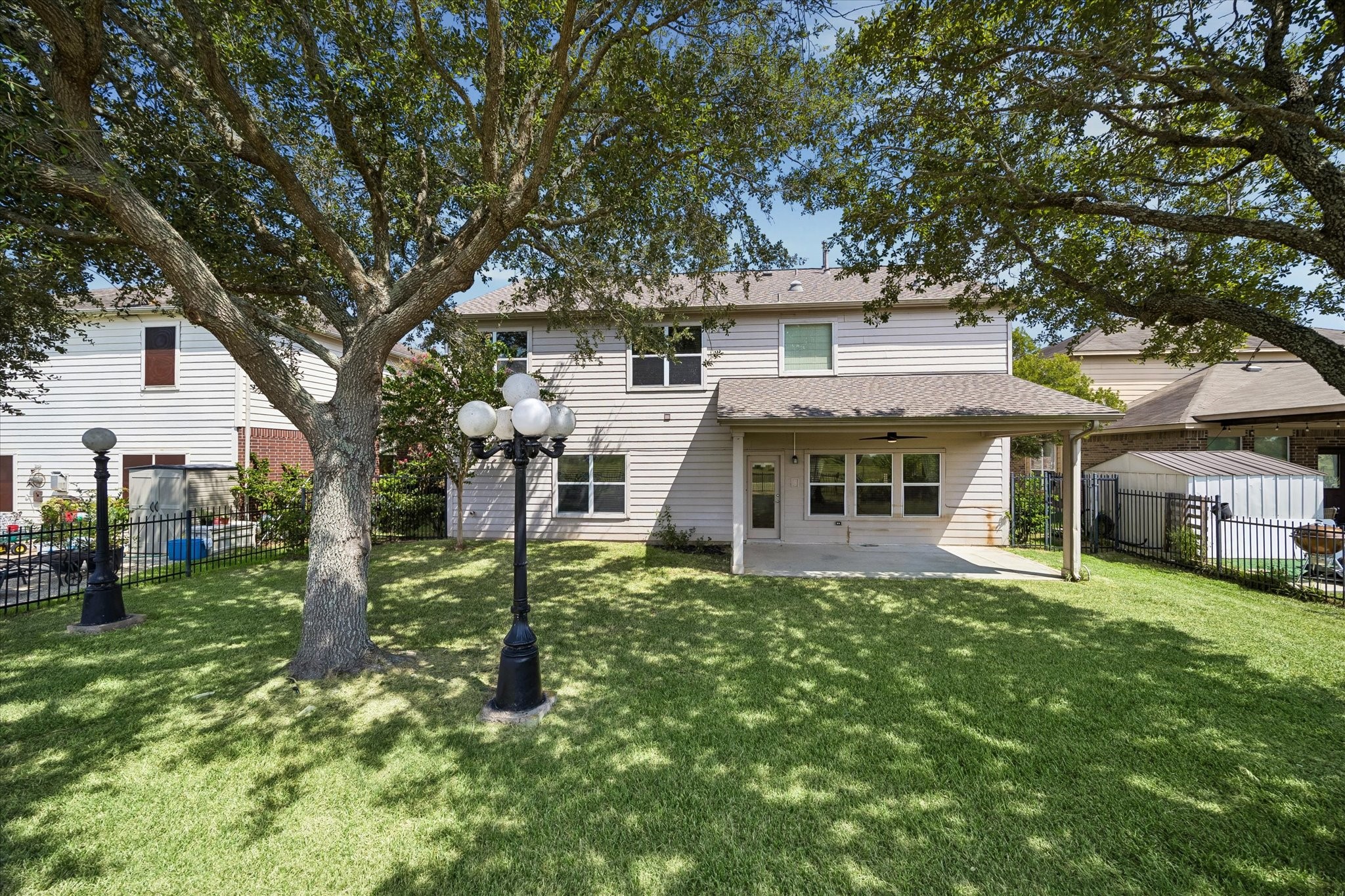 Charming two-story home with a spacious backyard, featuring a covered patio perfect for outdoor relaxation and mature trees providing ample shade.