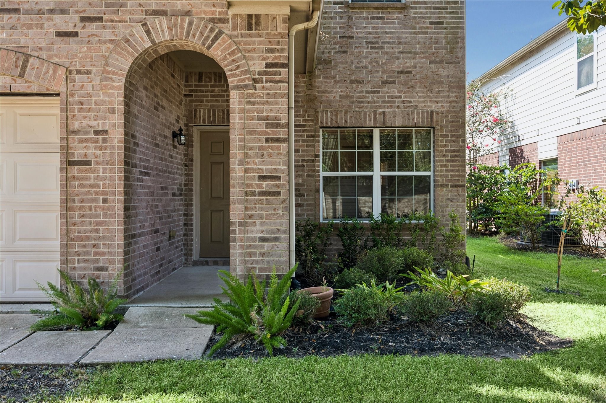 Charming brick exterior with an inviting archway and neatly landscaped yard offering a warm and welcoming entrance. Charming brick exterior with an inviting archway and neatly landscaped yard offering a warm and welcoming entrance.