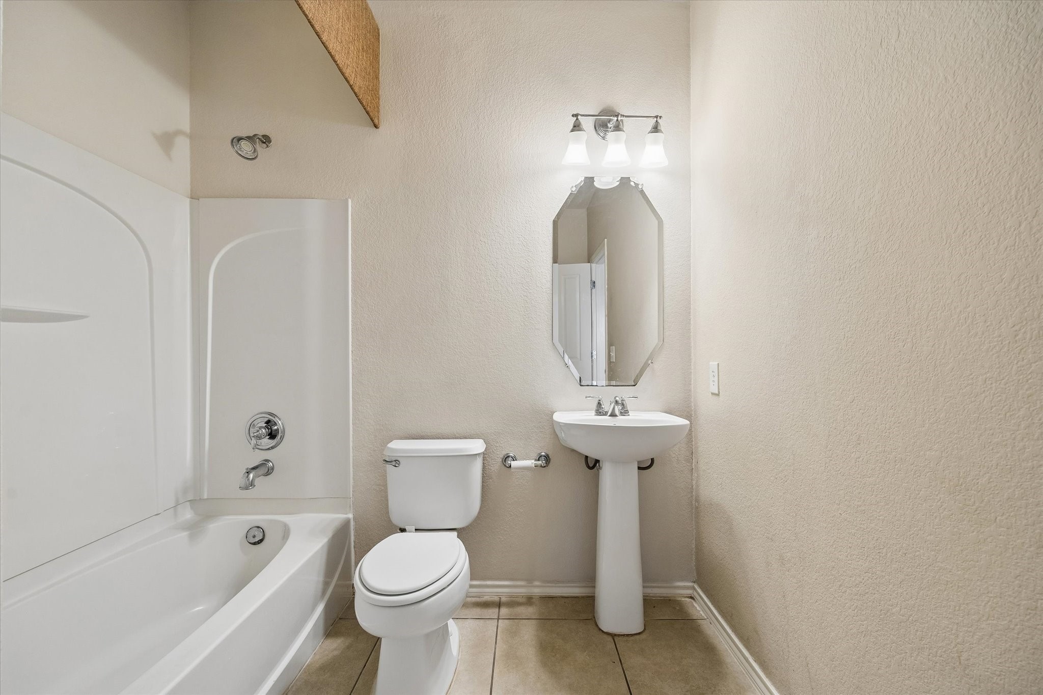 Elegant bathroom featuring a pristine bathtub, modern pedestal sink, and sleek fixtures, all complemented by soft neutral tones.